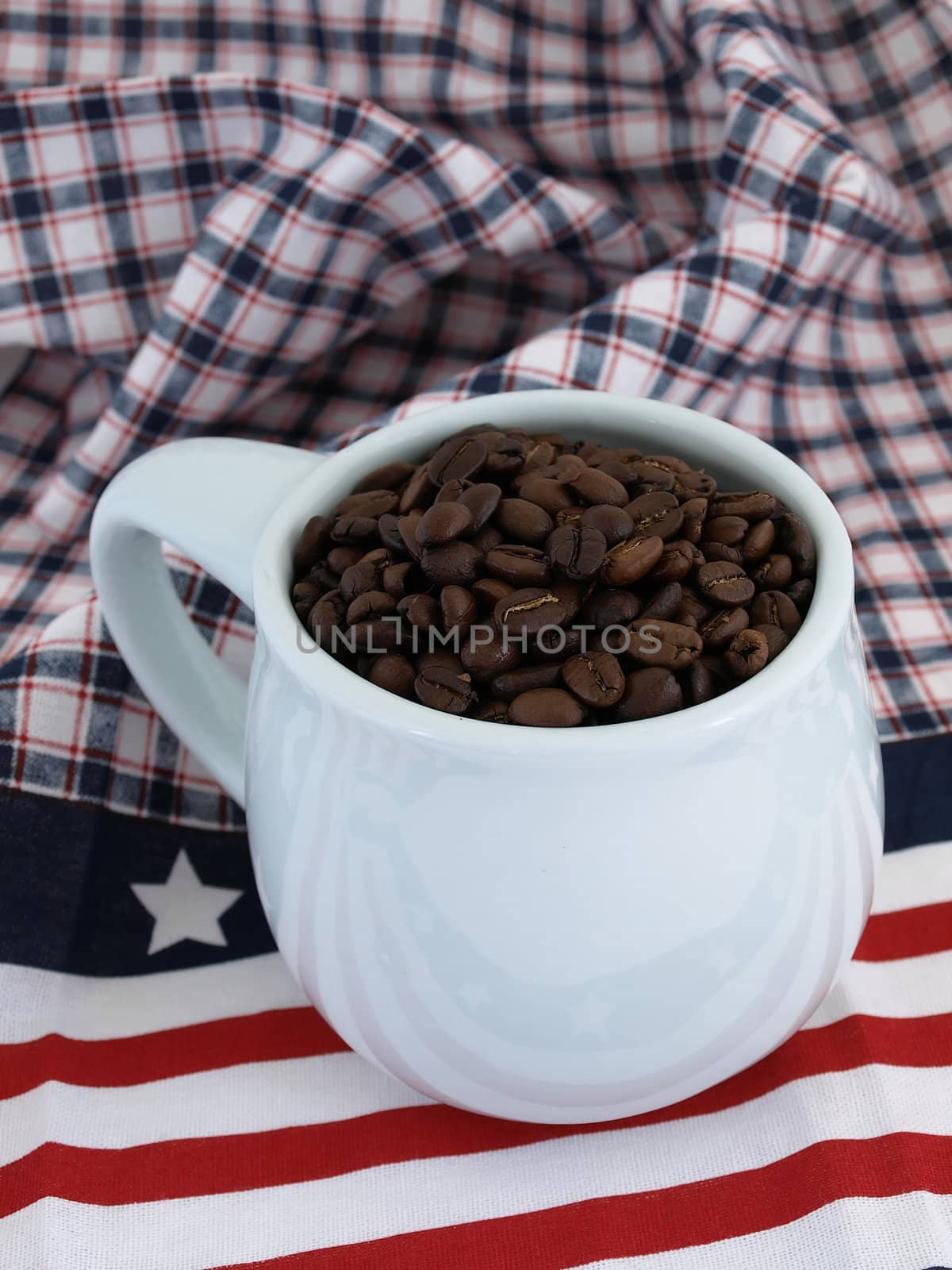 A blue coffee cup full of rich fresh beans over a red white and blue background.