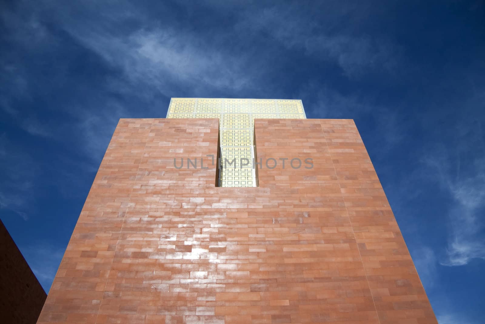 A brick tower with yellow glass and blue sky