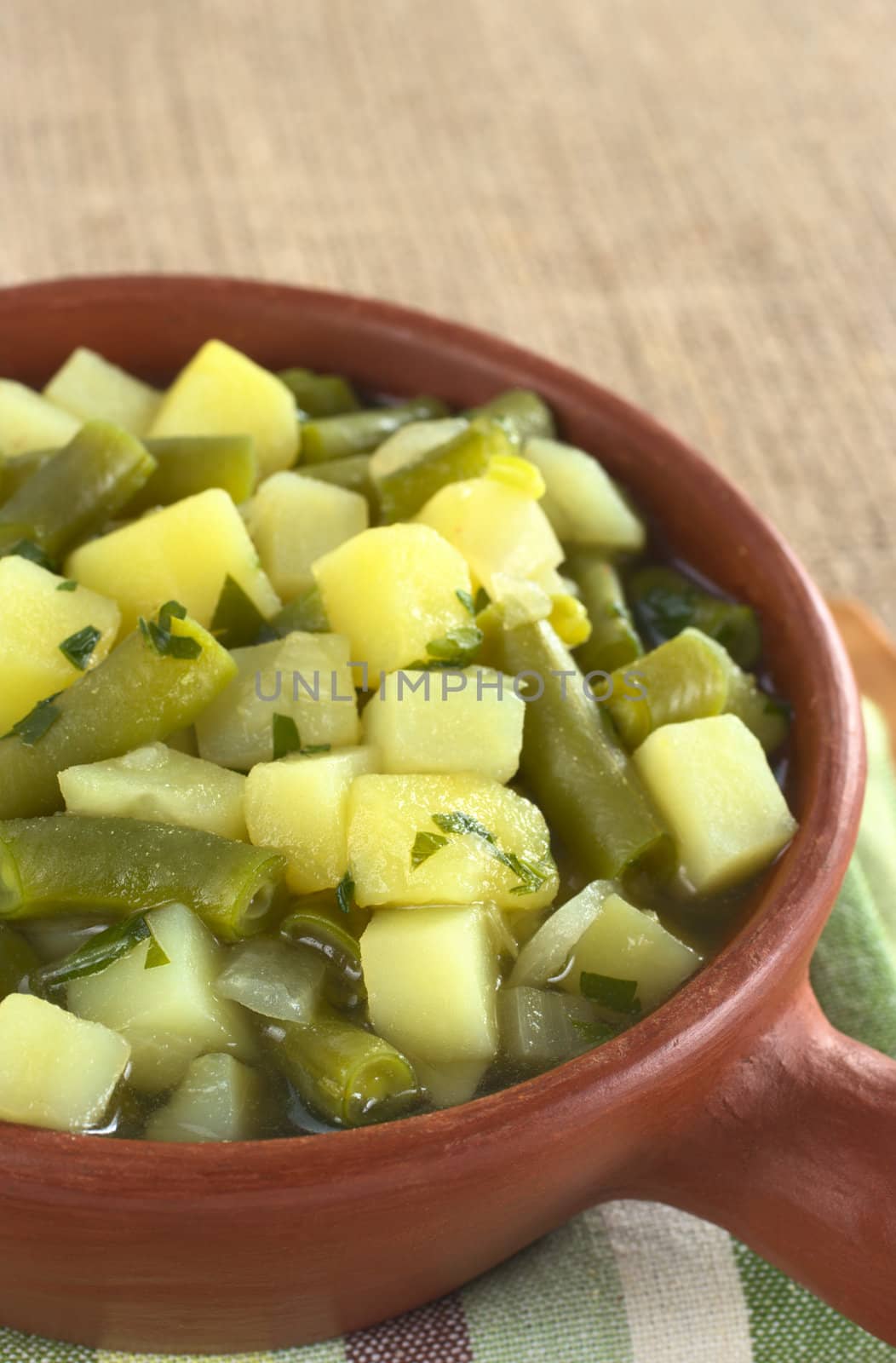 Potato-green-bean hotpot in rustic bowl on jute (Selective Focus, Focus one third into the hotpot)