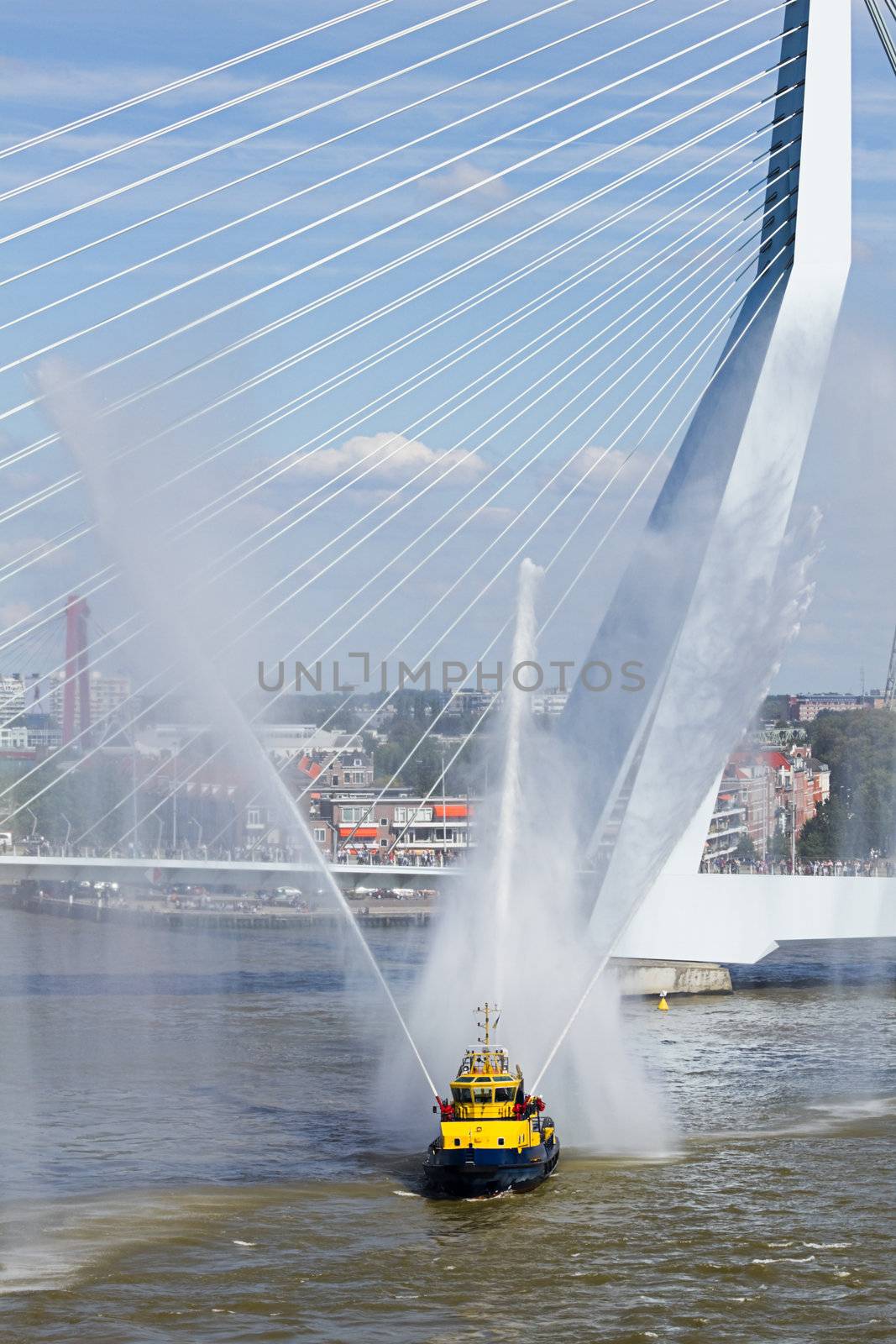 Firefightingboat demonstration on the river spraying jets of water with Erasmusbridge in background.