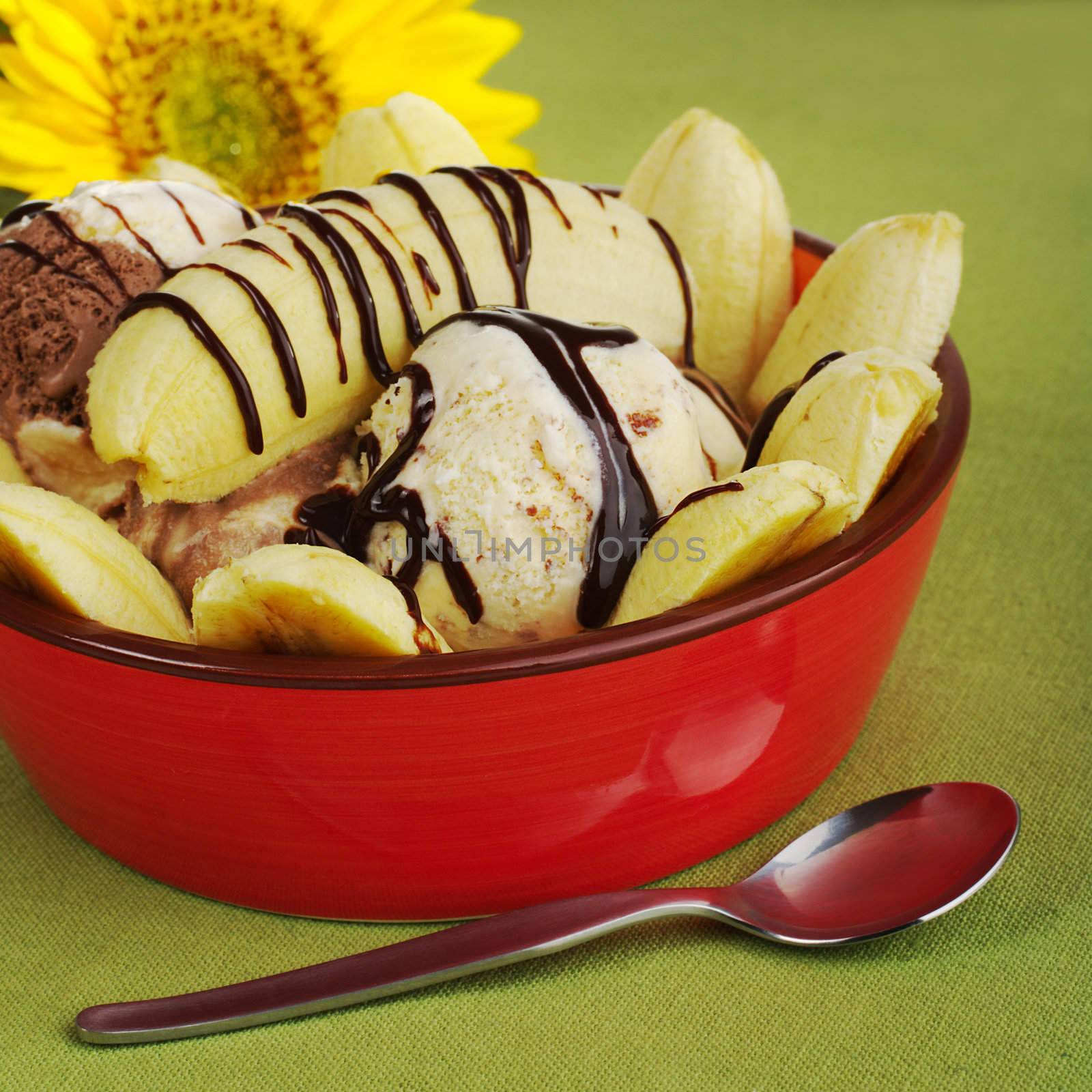 Dessert: Banana split in red bowl with spoon on green table mat and sunflower in the back ground (Selective Focus)