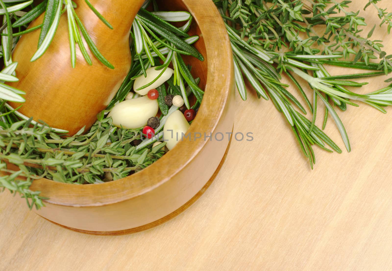 Mortar with garlic, peppercorns, rosemary and thyme on wooden board (Selective Focus)  