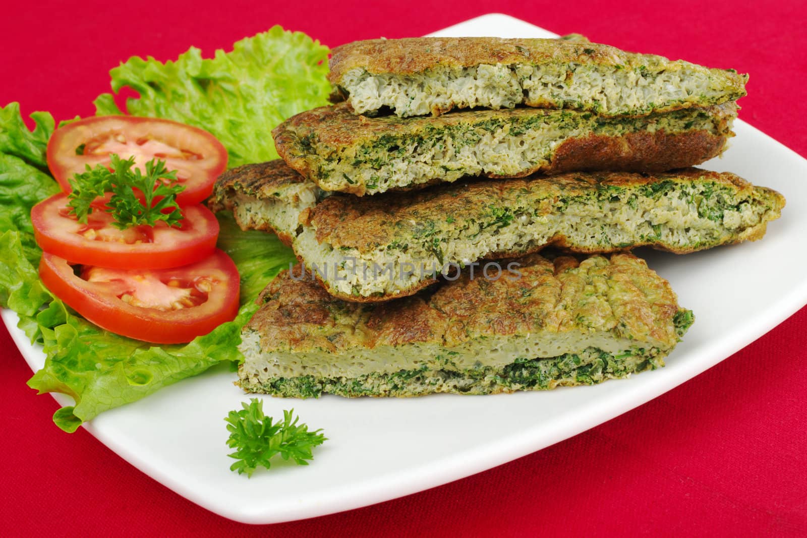 Omelette with herbs with parsley, lettuce and tomato slices, on white plate and red tablecloth (Selective Focus)