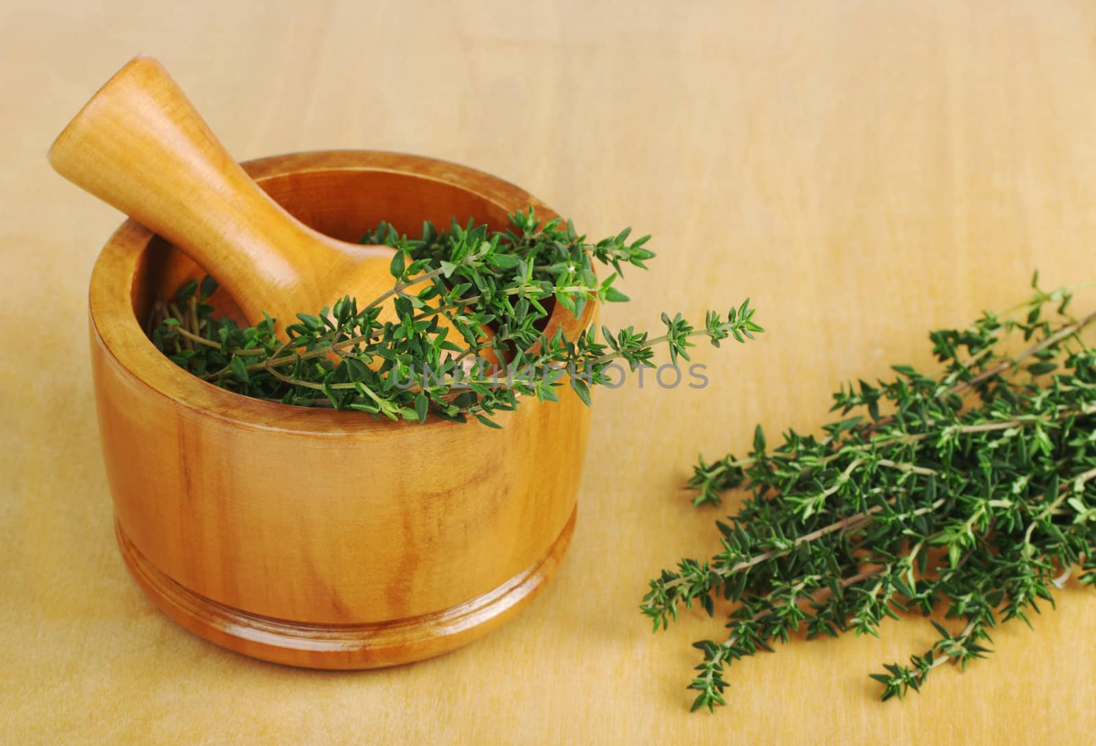 Fresh thyme with wooden mortar and pestle on wooden board (Selective Focus)