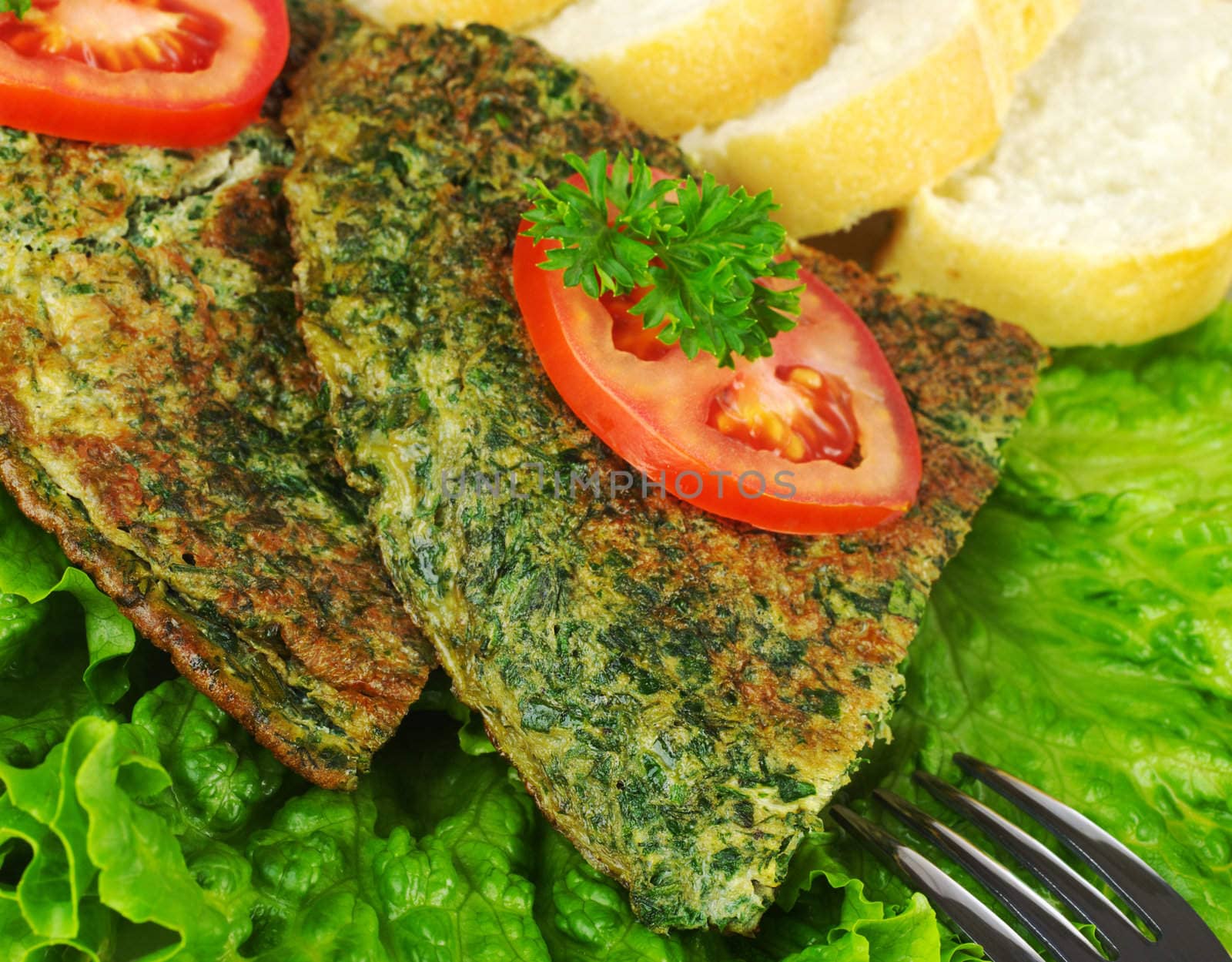 Omelette with herbs with lettuce, tomato, parsley and baguette and fork photographed from above (Selective Focus)