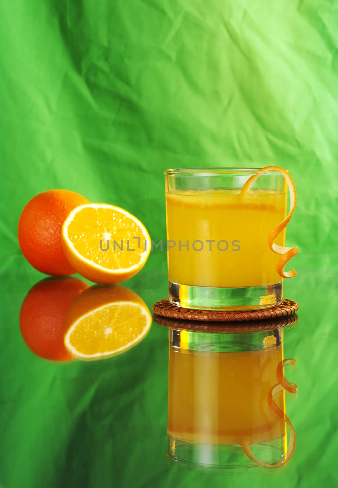 Fresh orange juice with oranges with reflection on green background (Selective Focus) 