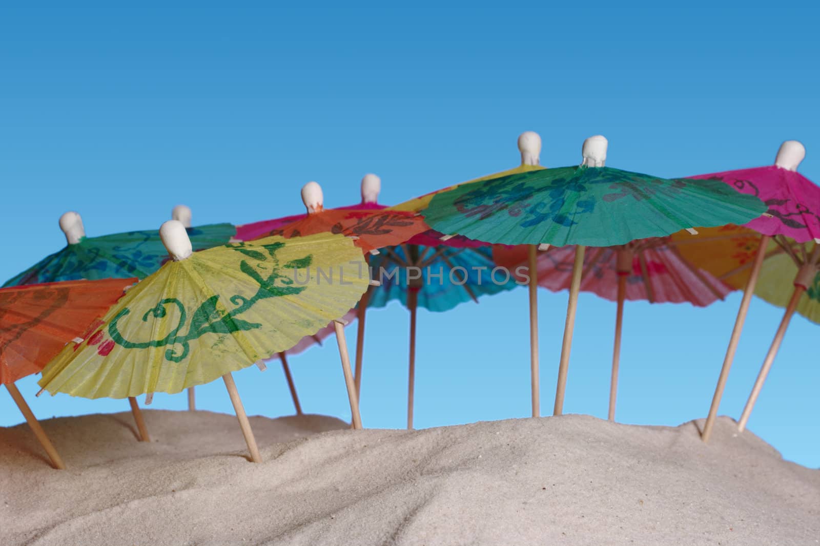 Colorful sunshades on sand and a blue background (Selective Focus)