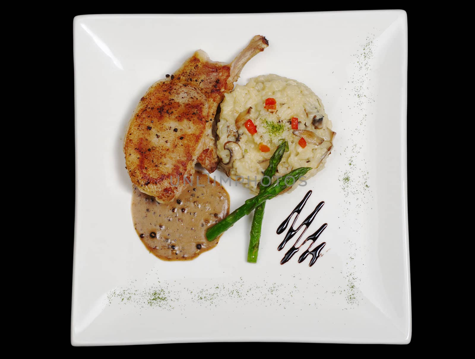 Main dish: Chop with sauce, rice and asparagus on black background