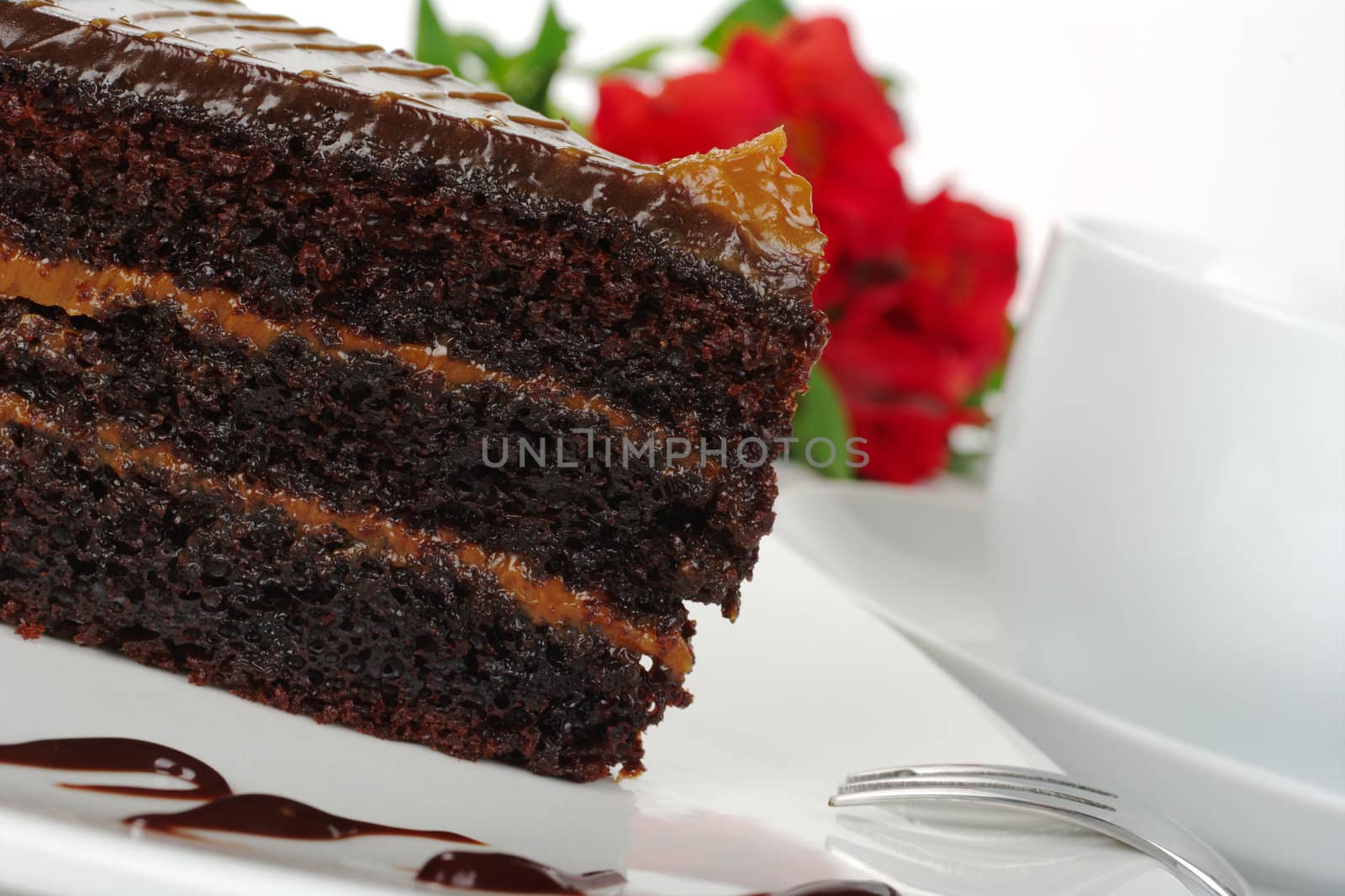 Chocolate cake with coffee and a red Inca Lily in the background (Selective Focus)