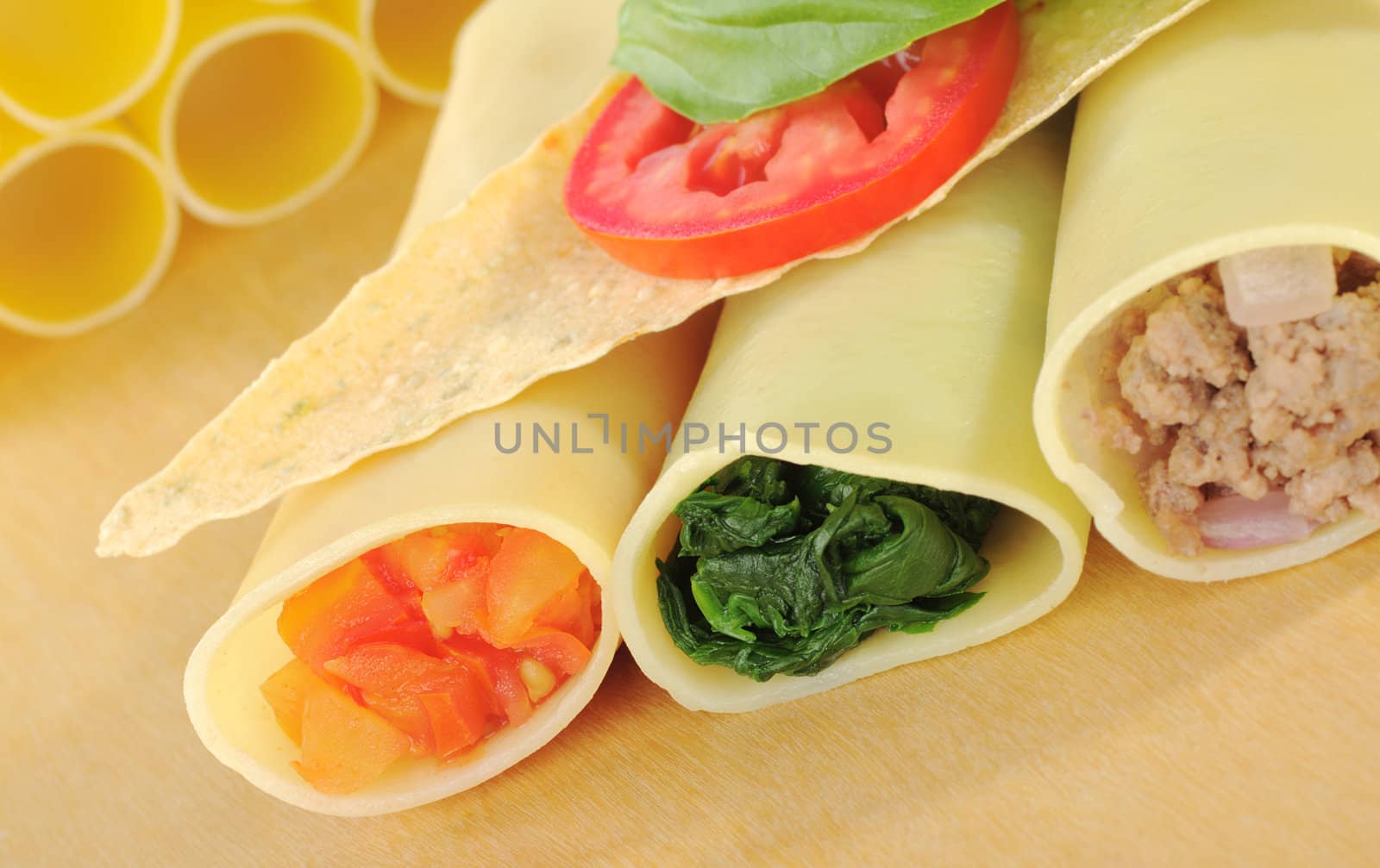 Cannelloni filled with tomatoes, spinach and mincemeat, with crocantini, tomato and basil leaf on top (Selective Focus)