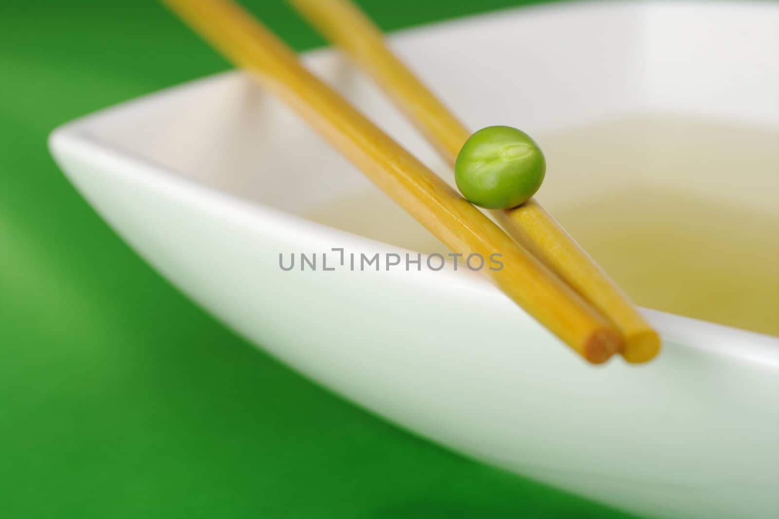 Chinese diet: Vegetable Broth in soup plate with chopsticks and pea  (Selective Focus)