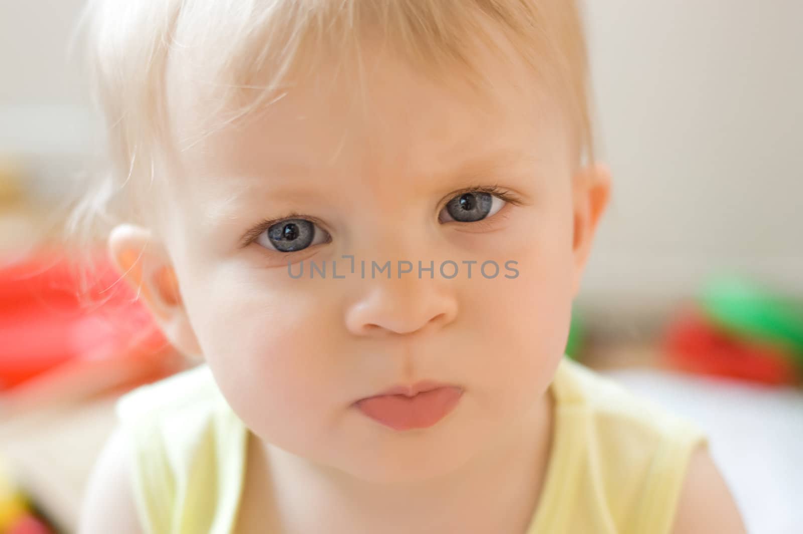 Serious baby girl face over colorful back, soft focus