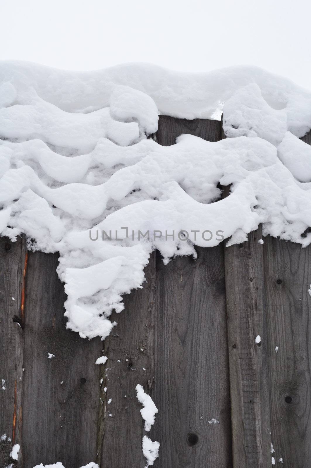 Winter natural photo: snow frozen to a wooden fence