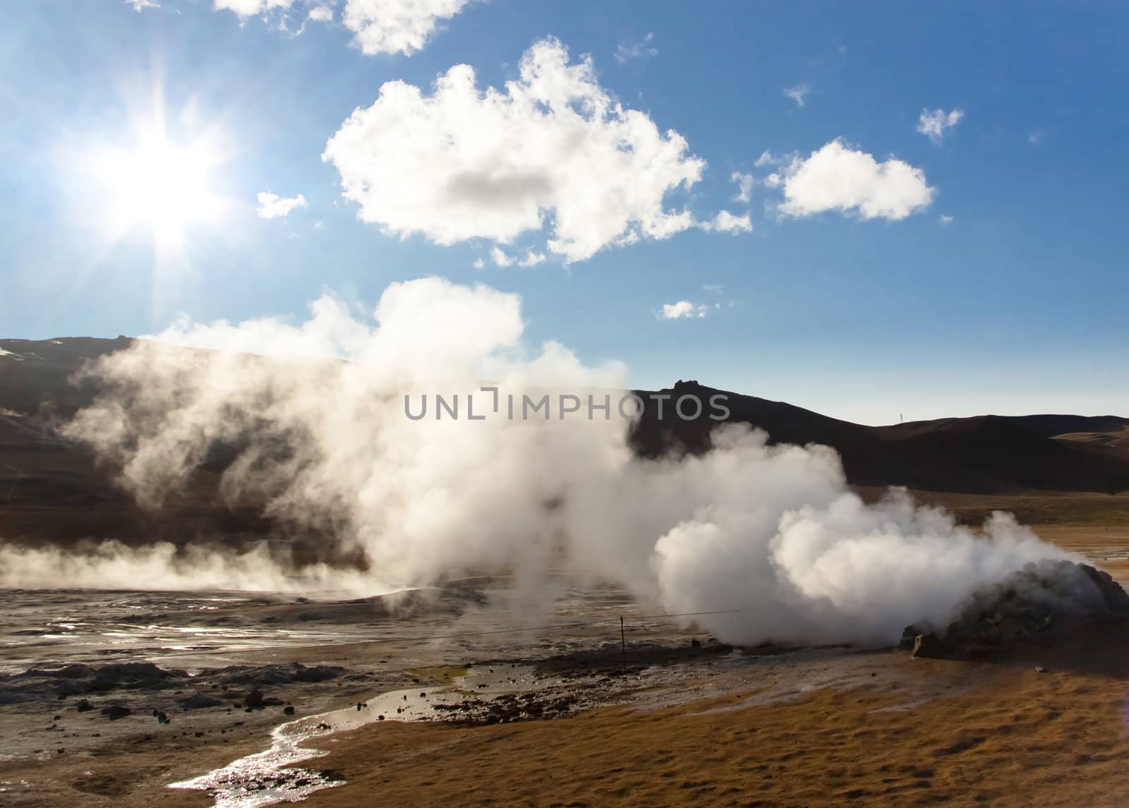 Steam at high pressure of the Sulphurous hill Namafjall in Iceland. Blue sky with sun.