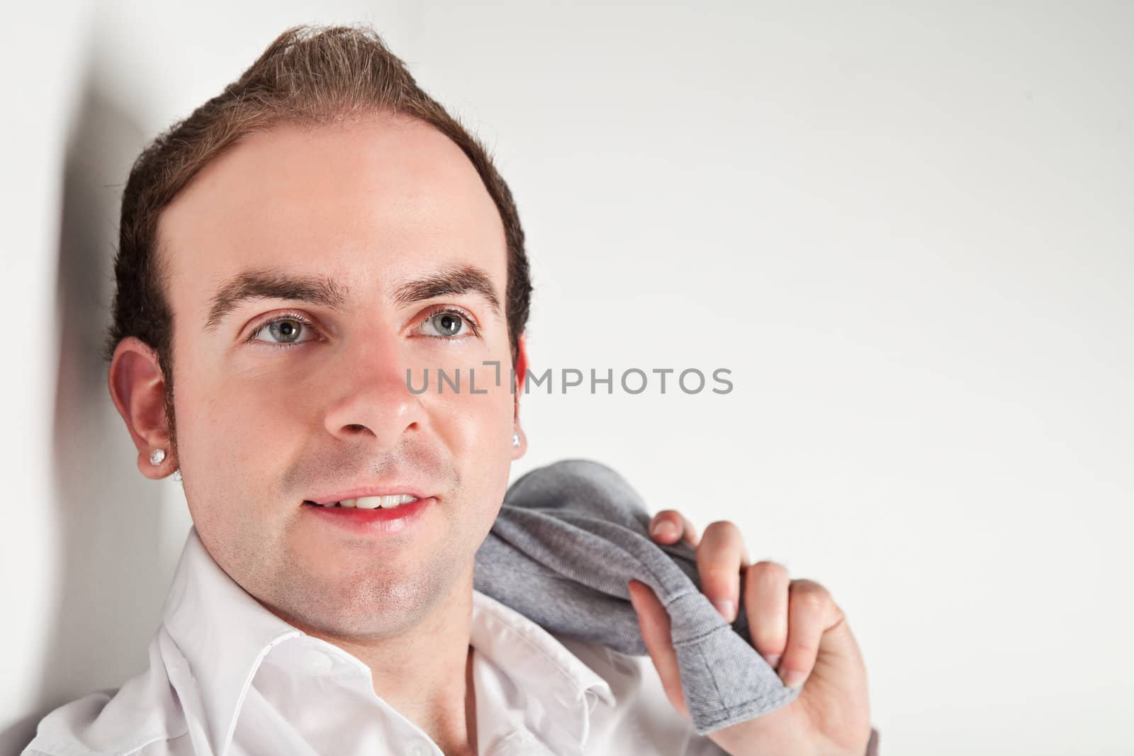 Portrait of relaxed young man leaning to white wall