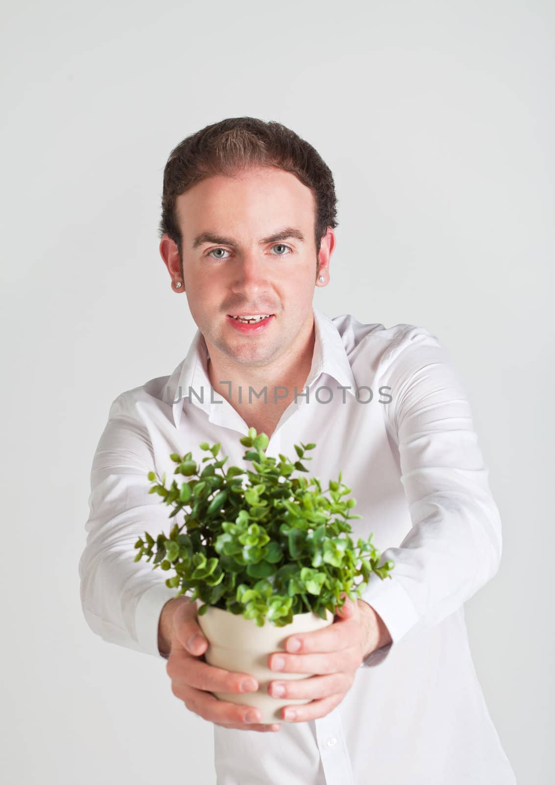 Happy young man holds a pot with decoration plant