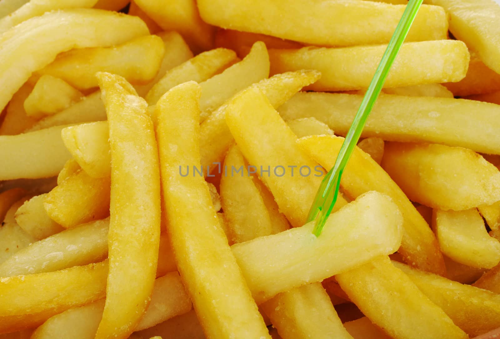 French fries with a green skewer from close (Selective Focus, Focus on Front)