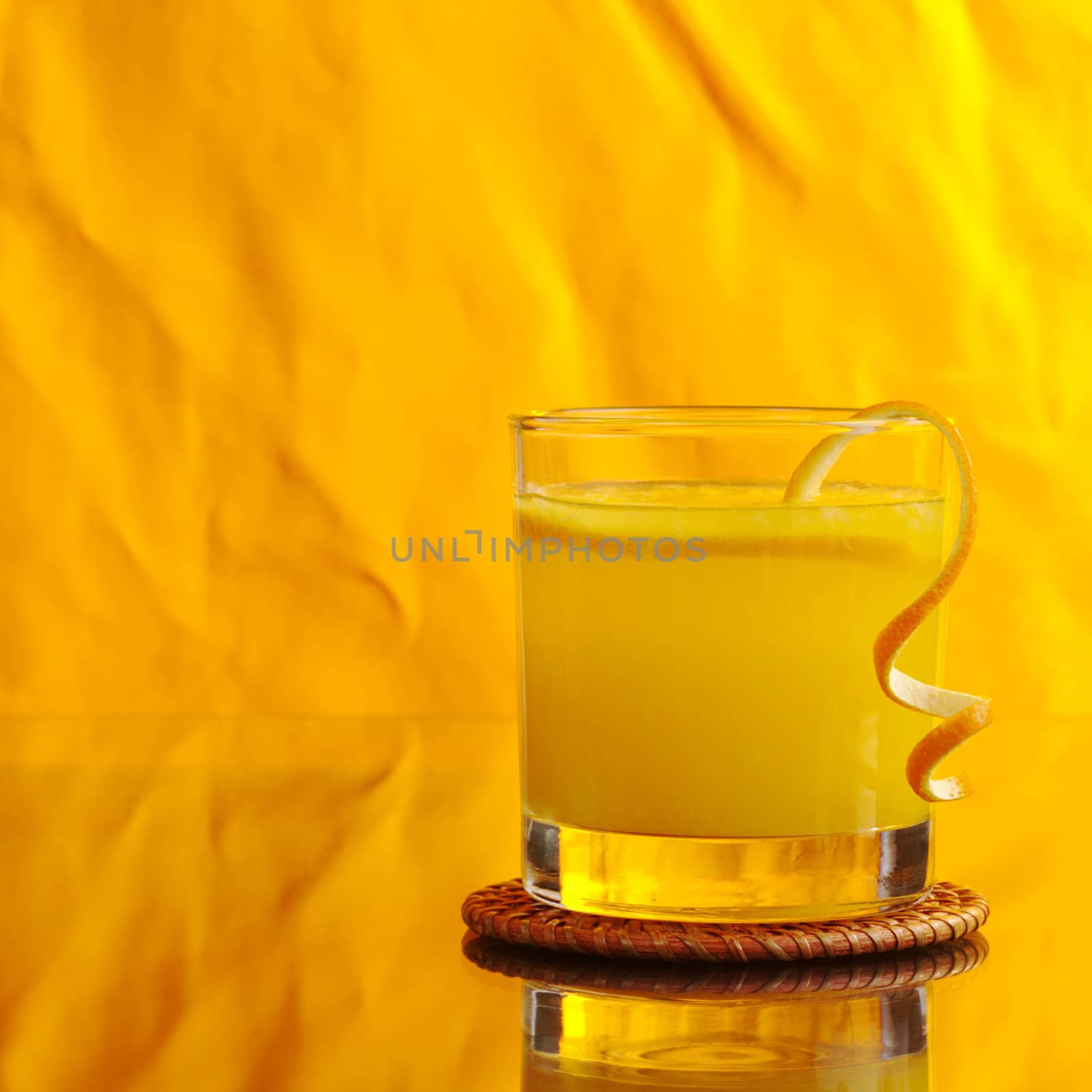 Fresh orange juice in glass with orange peel on orange background (Selective Focus) 