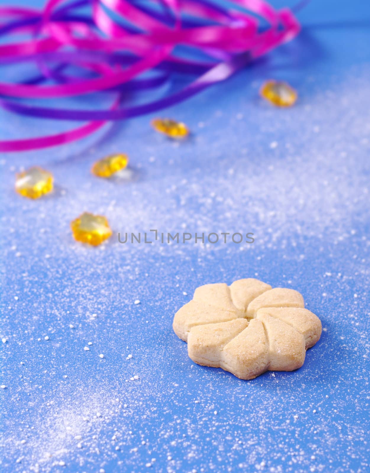 Star-shaped cookie on blue with powder sugar, yellow stones, and ribbons (Selective Focus)  