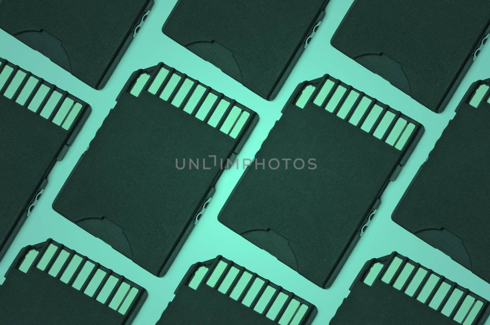 Close up on a pattern of black SD memory cards arranged with green filter