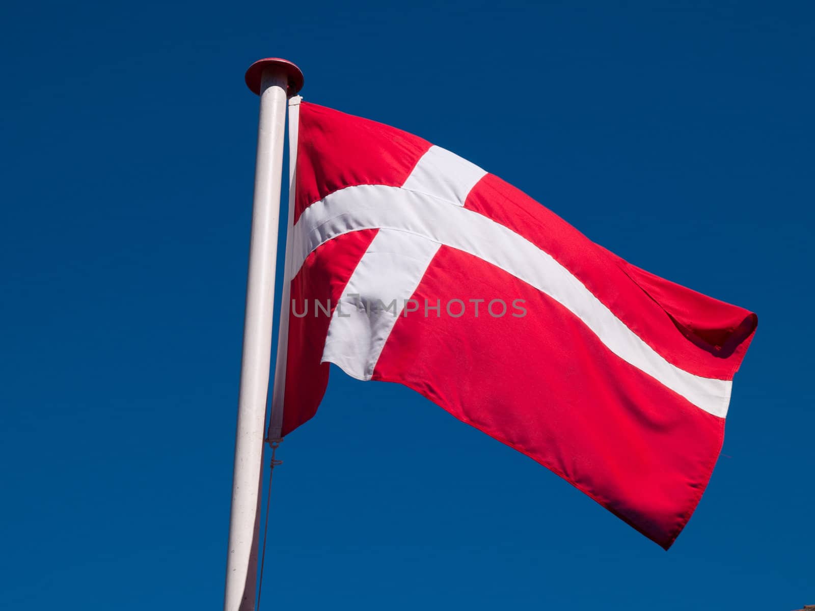 Flag of Denmark up high in the air with clear blue sky background