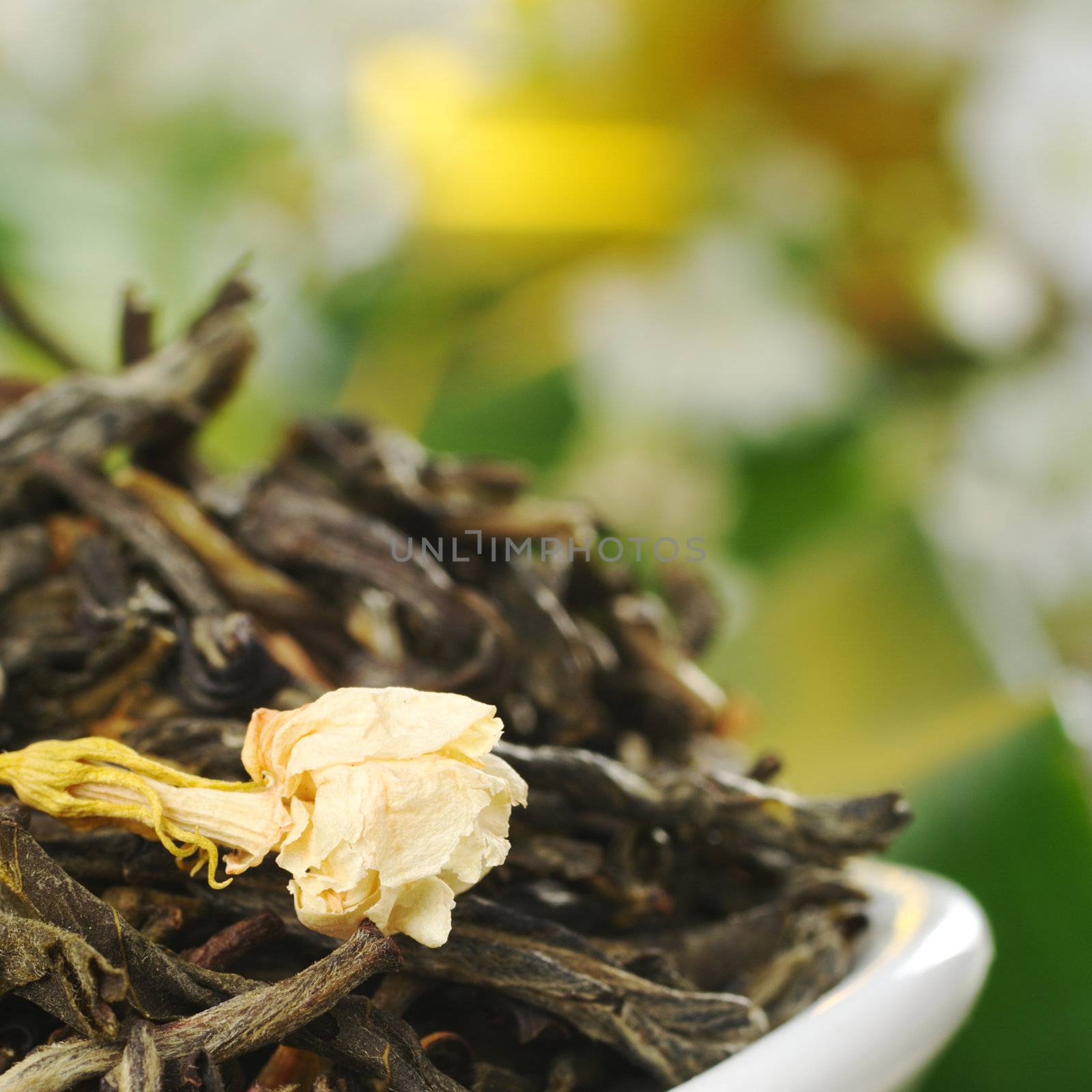 Loose green tea with jasmine flowers with some white flowers in the background (Selective Focus, Focus on the jasmine flower) 