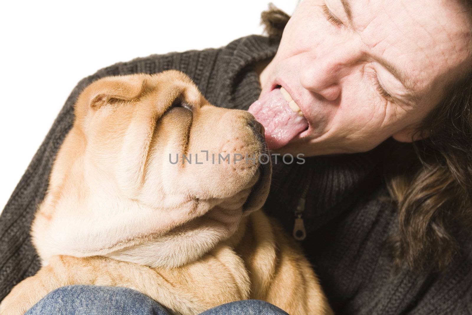 A funny young man licking a sharpei puppy over the head