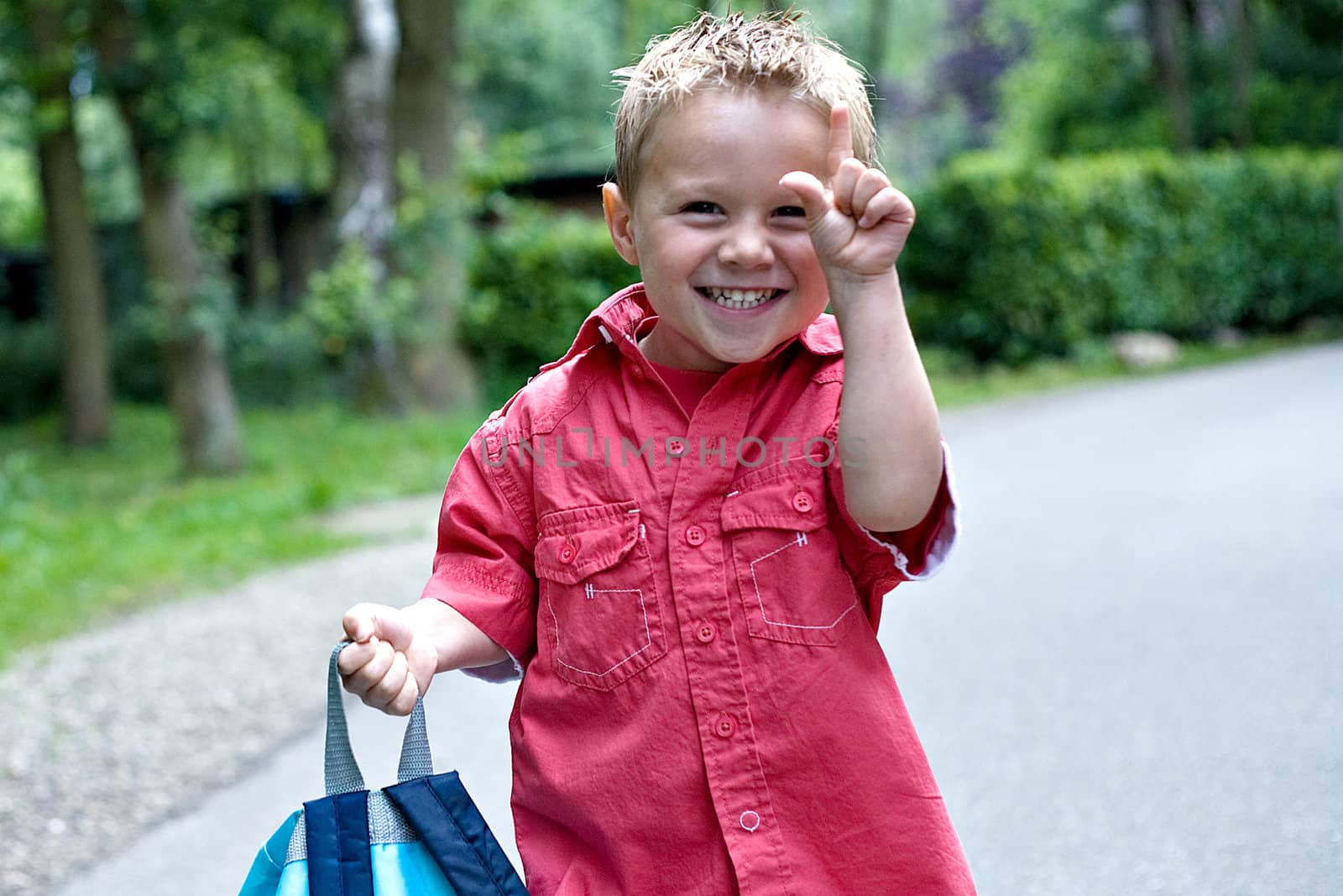 Portrait of a funny kid making a sign.