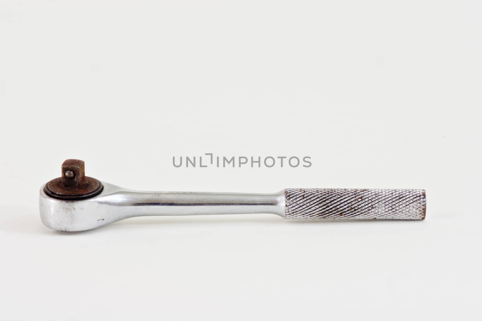 A well used socket wrench on a white background.