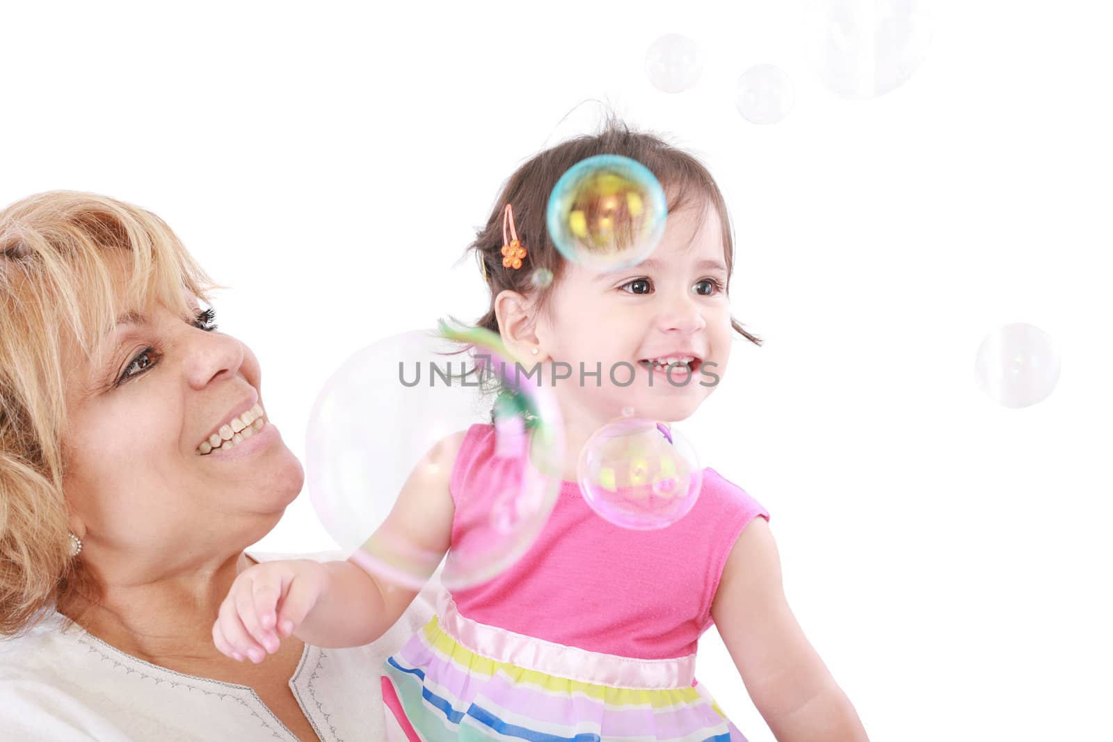 Aunt and a little girl enjoy looking at bubbles floating in the by dacasdo
