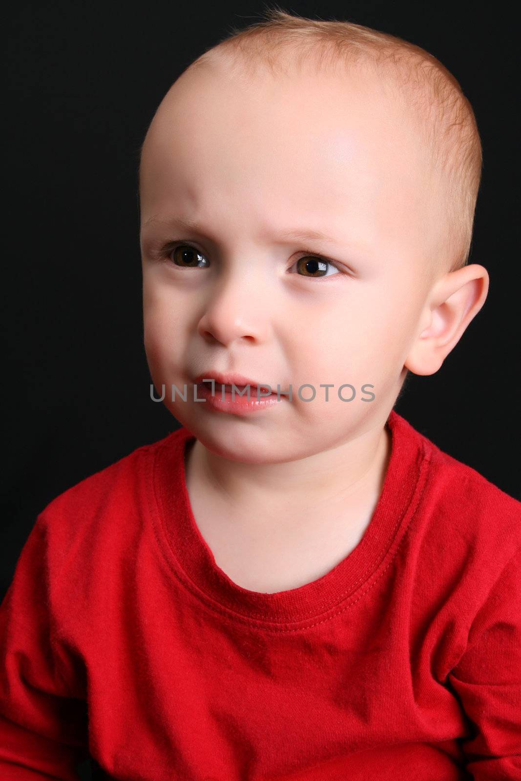 Cute toddler wearing a red shirt with a frown