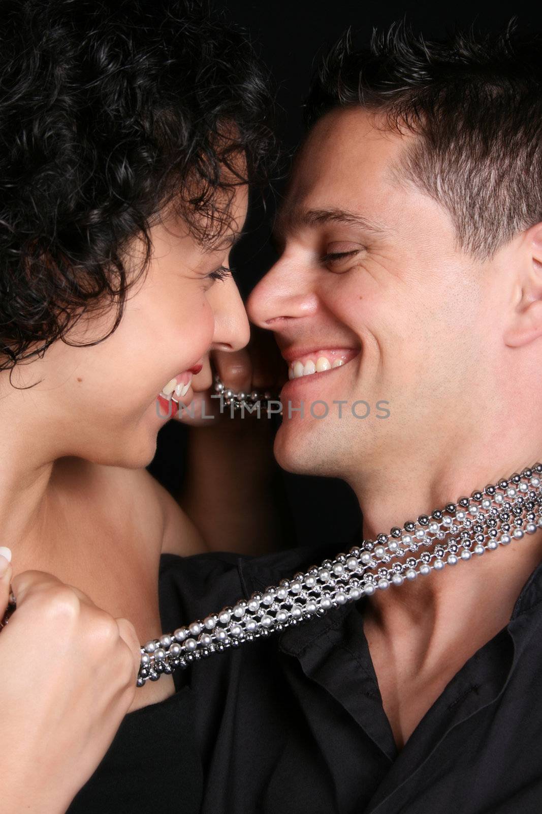 Beautiful young couple laughing with their faces close to one another
