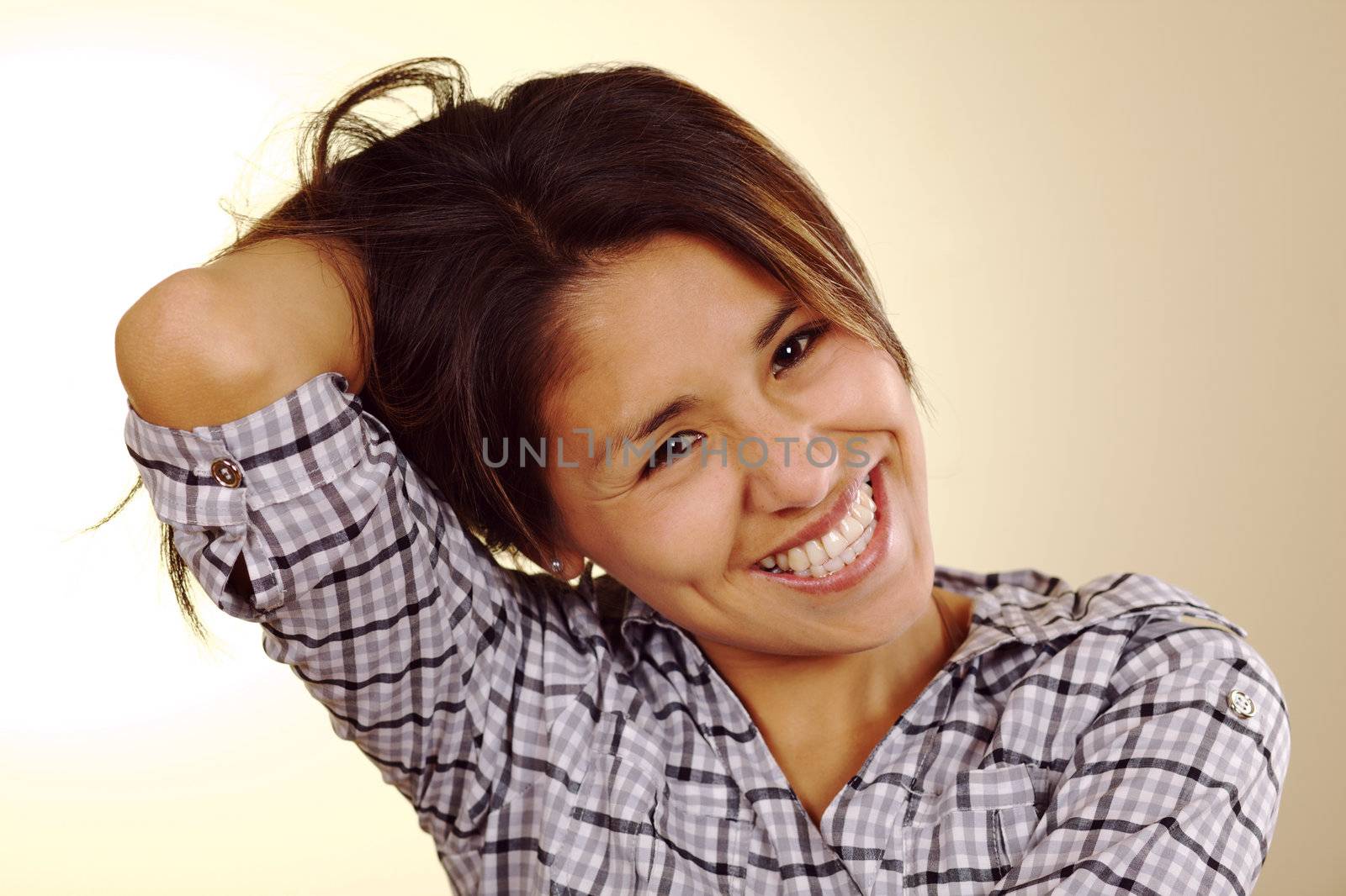 Beautiful young Peruvian woman laughing and holding up her hair in the back with one hand (Selective Focus, Focus on the eyes)