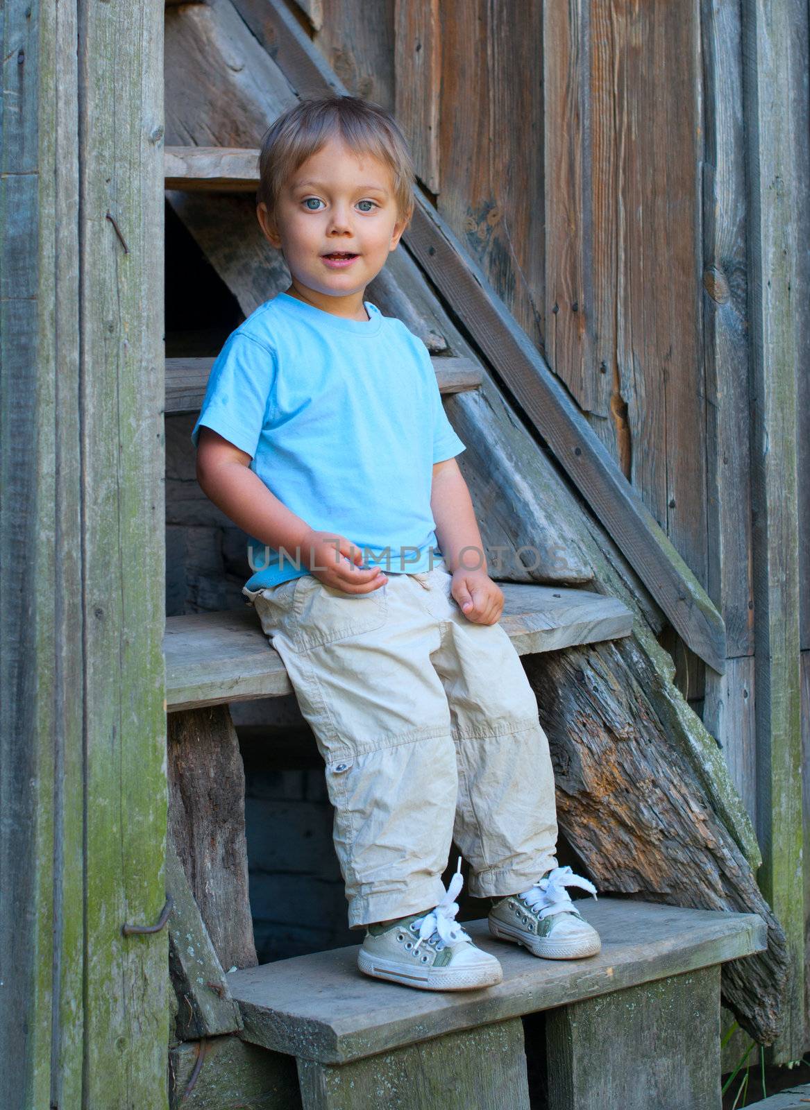 Cute 2 years old boy sitting on the the steps in the park