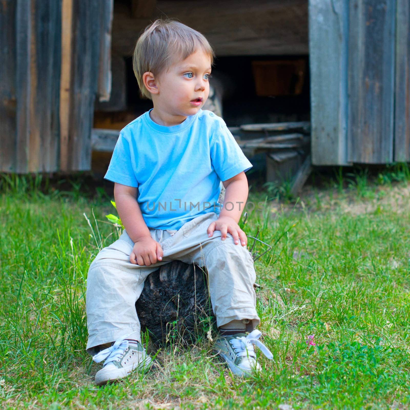 Cute 2 years old boy sitting on the the bench in the park