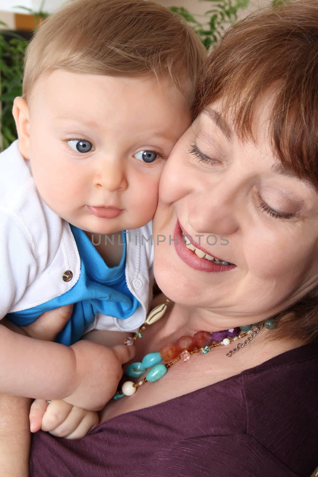 Beautiful blond baby boy sitting by his grandmother