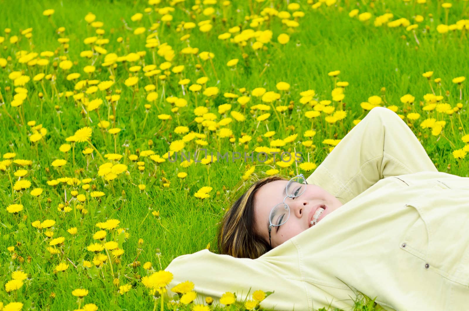 A young preteen girl is lying in the grass, relaxing in the sun.