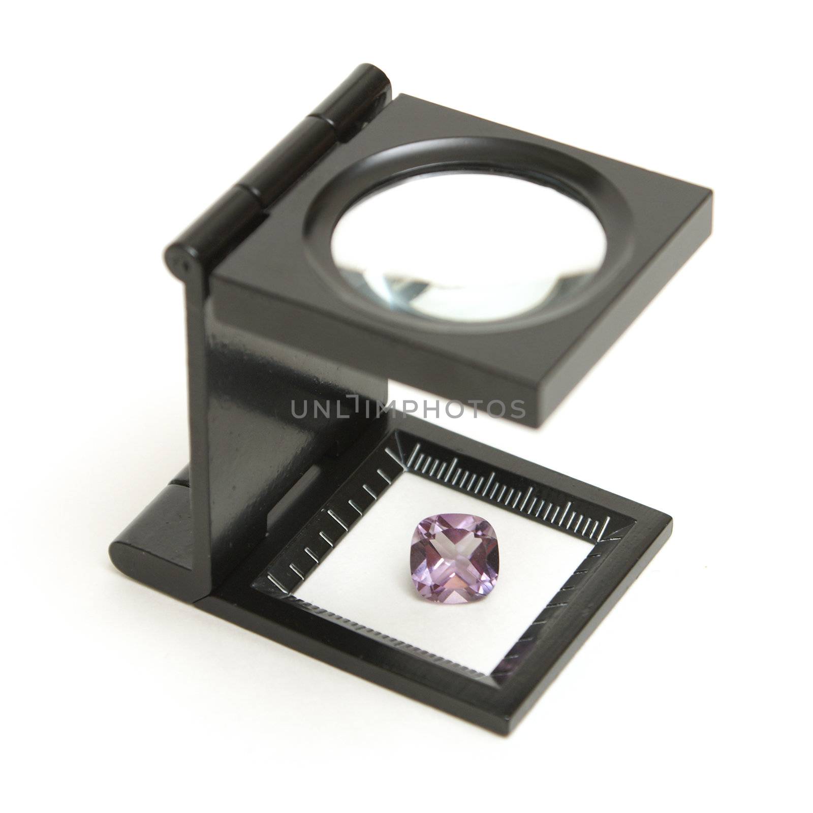 A loupe inspection of a finely cut amethyst gemstone to understand its value.