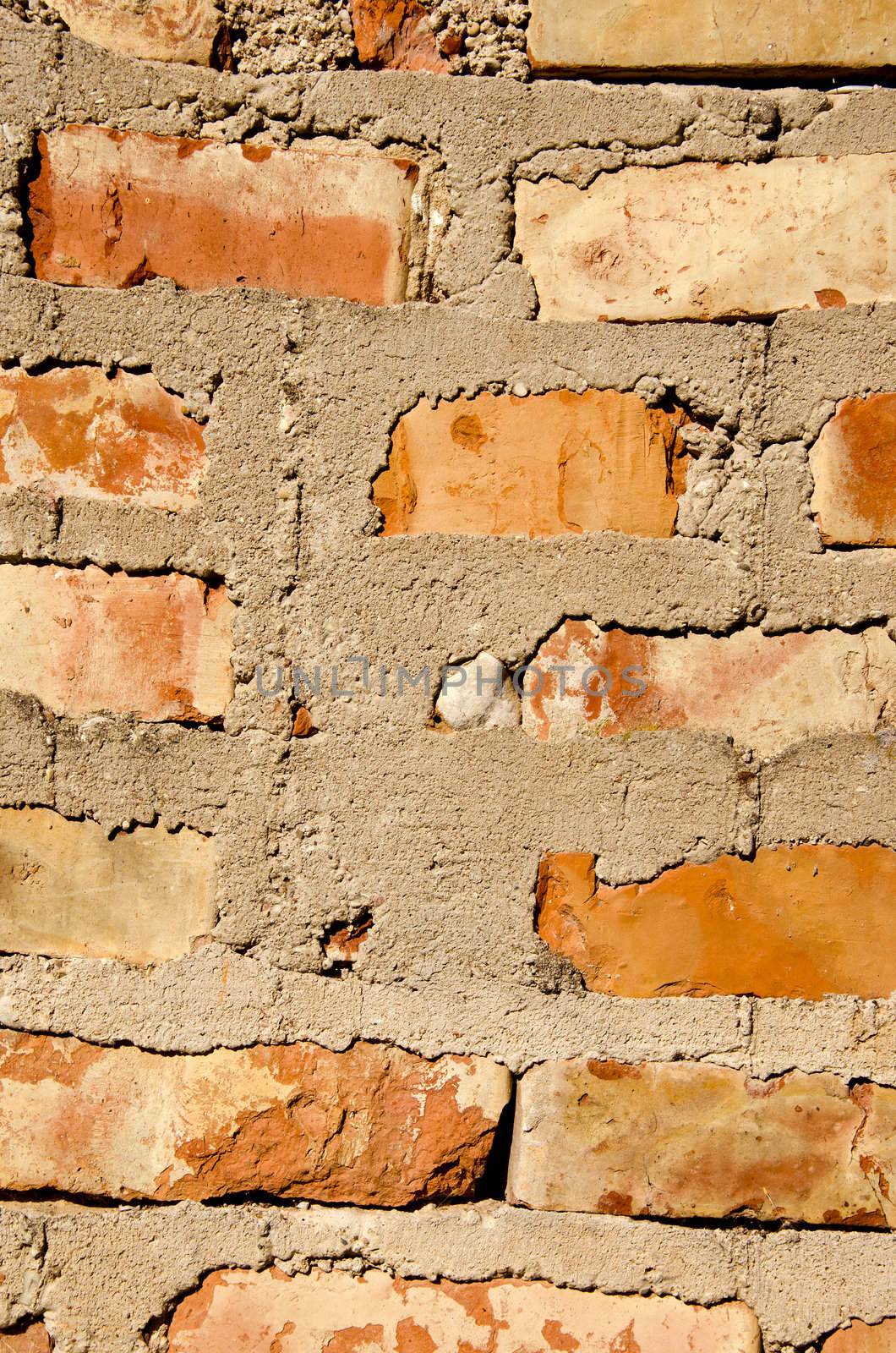Fragment of old squared red brick wall with many cement on it.