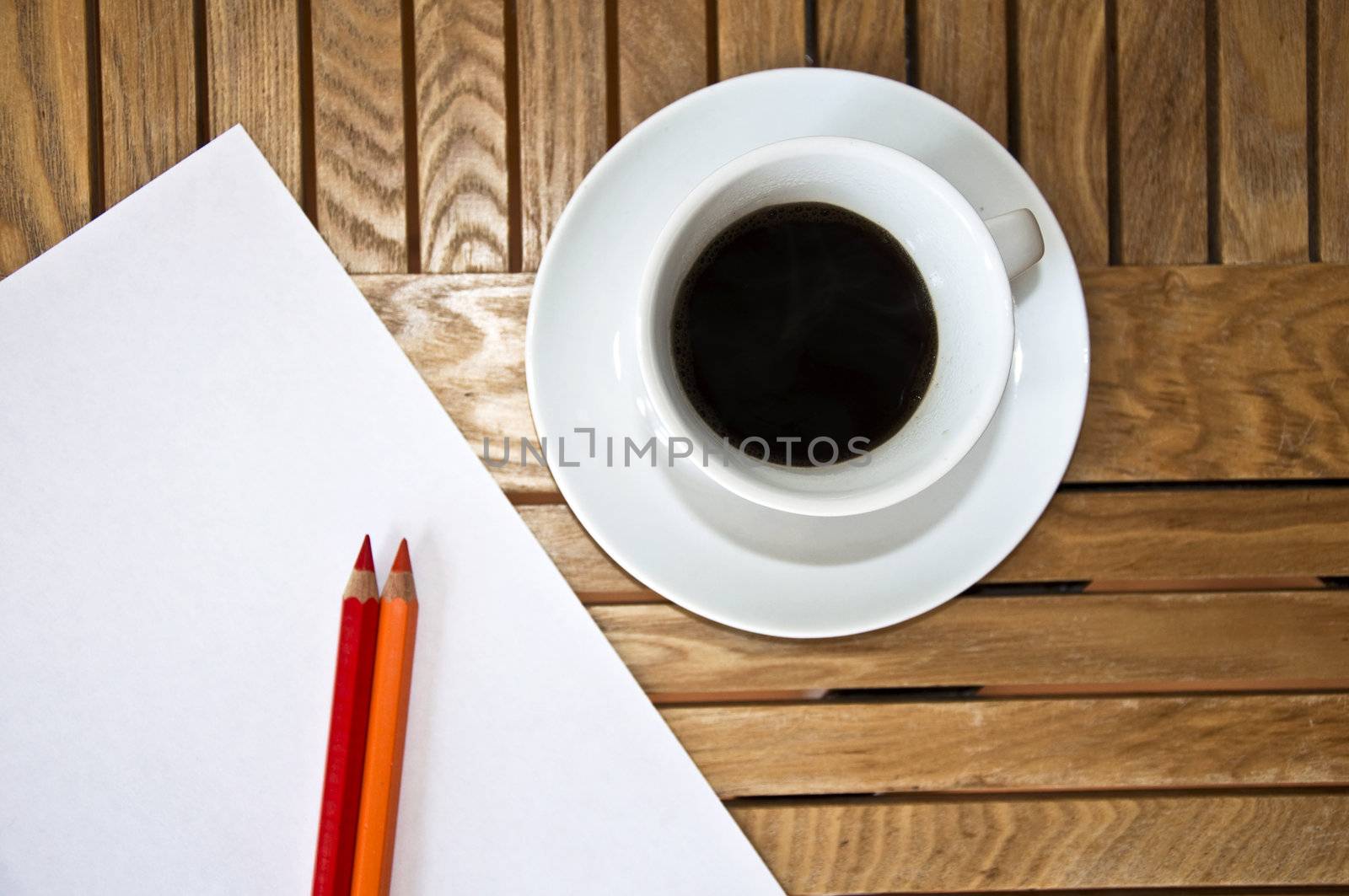 Paper blank Sheet, color pencil and a cup of coffee on a wooden table.