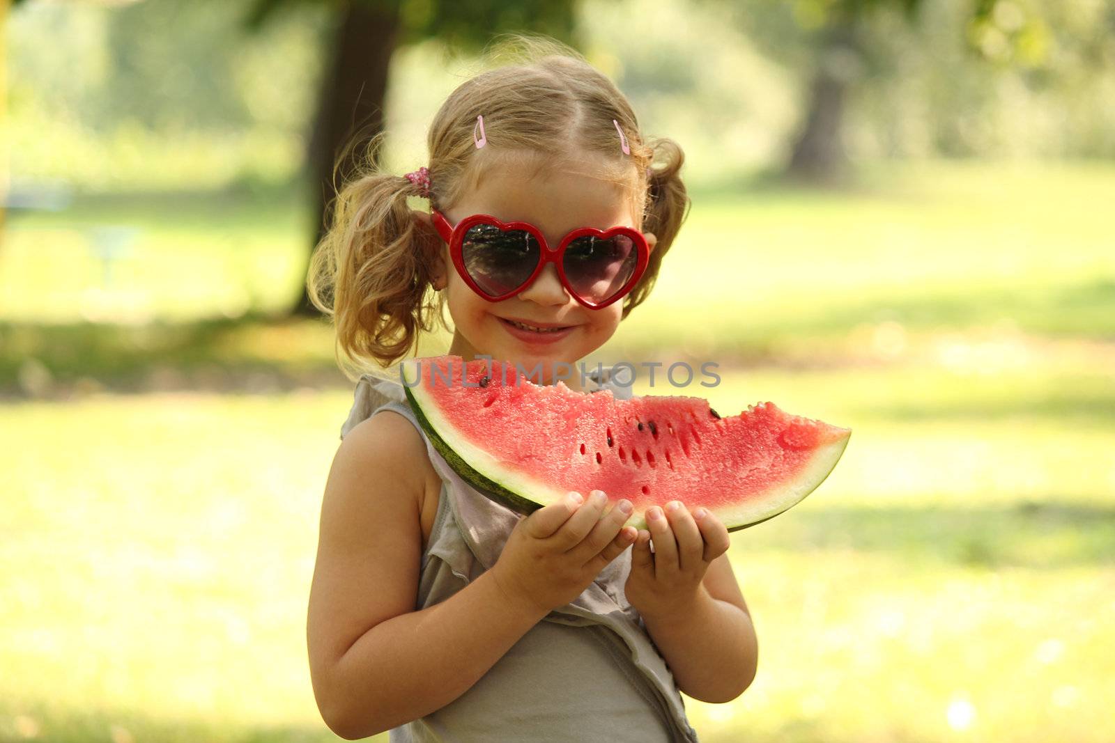 little girl with sunglasses eat watermelon by goce