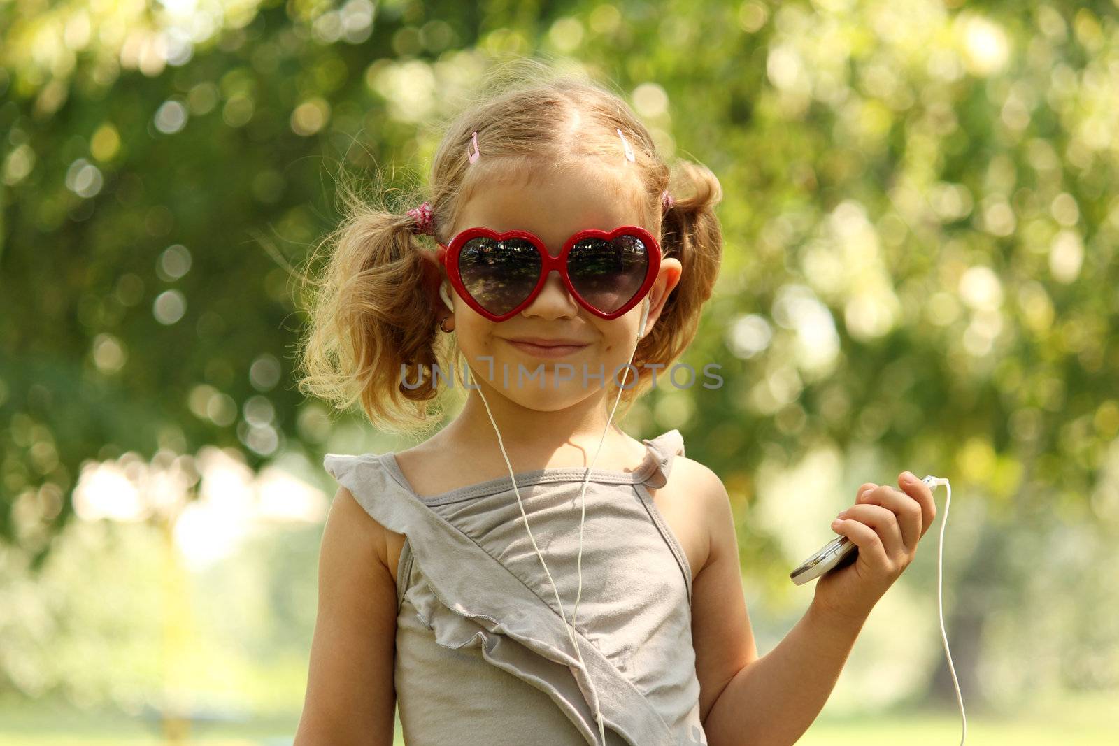 little girl with sunglasses listening music by goce