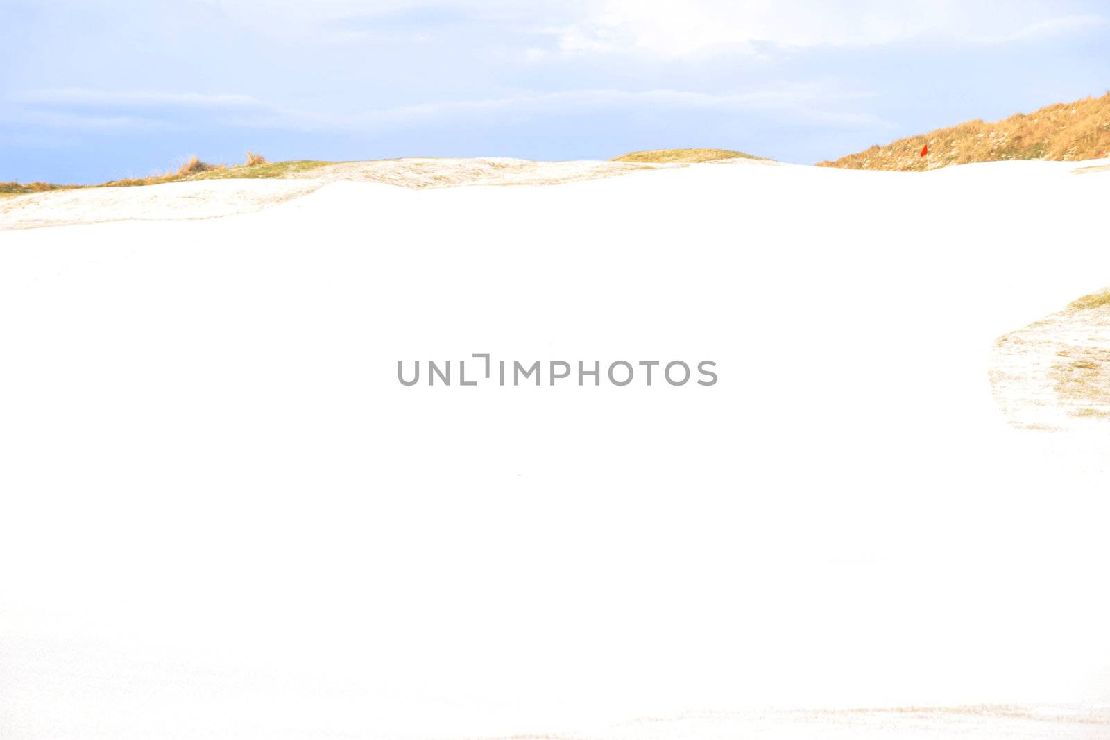 a snow covered links golf hole in ireland in winter weather with red flag