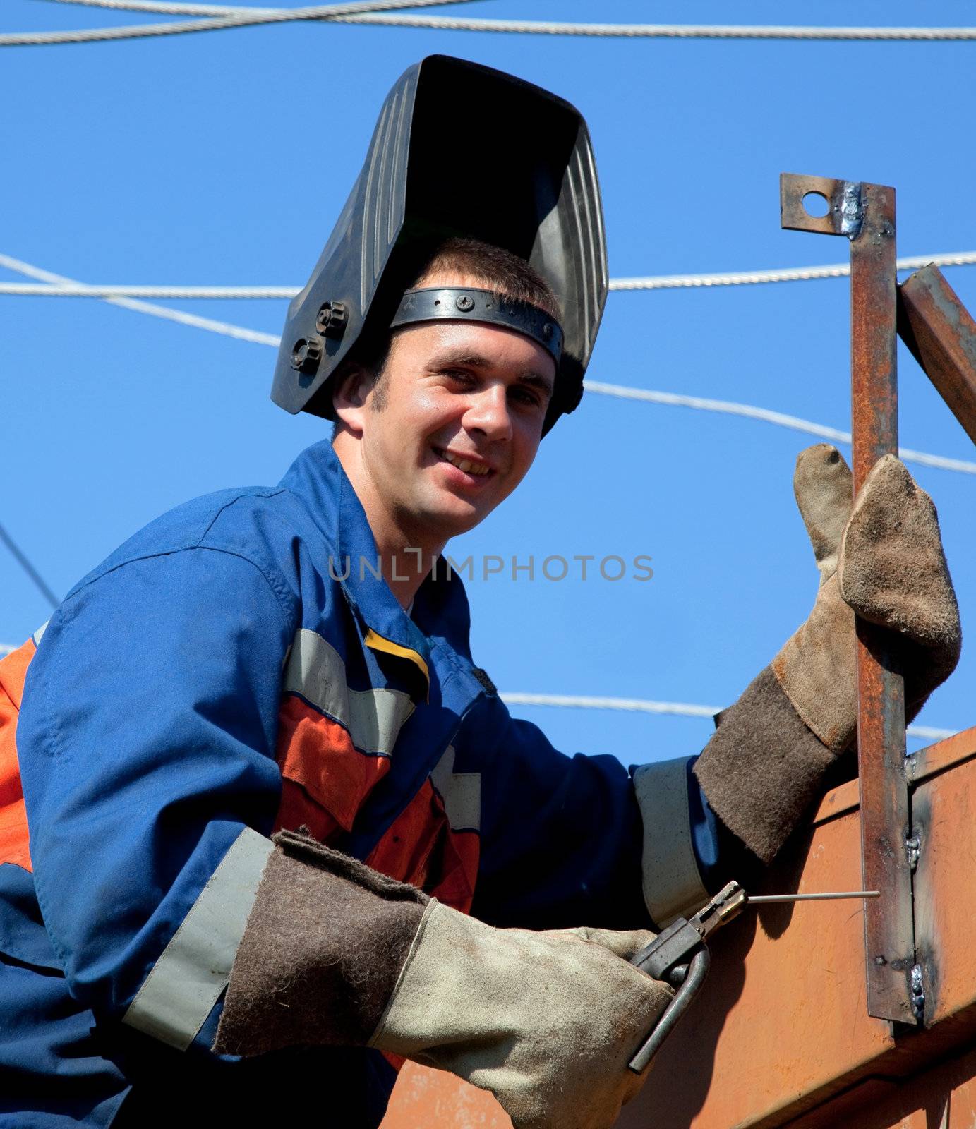 A welder working at height on a background of blue sky