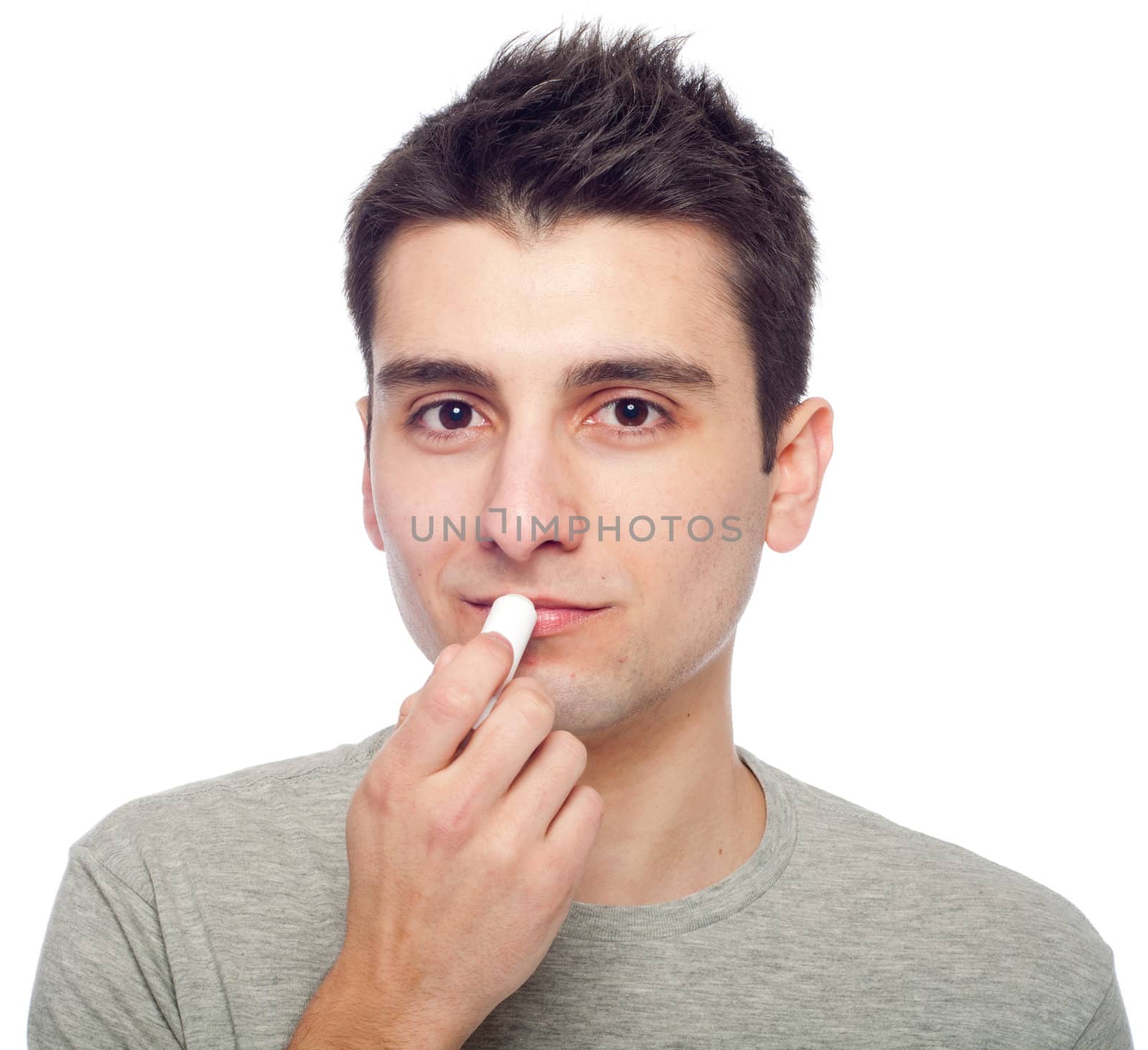 handsome young man applying lip balm (isolated on white background)