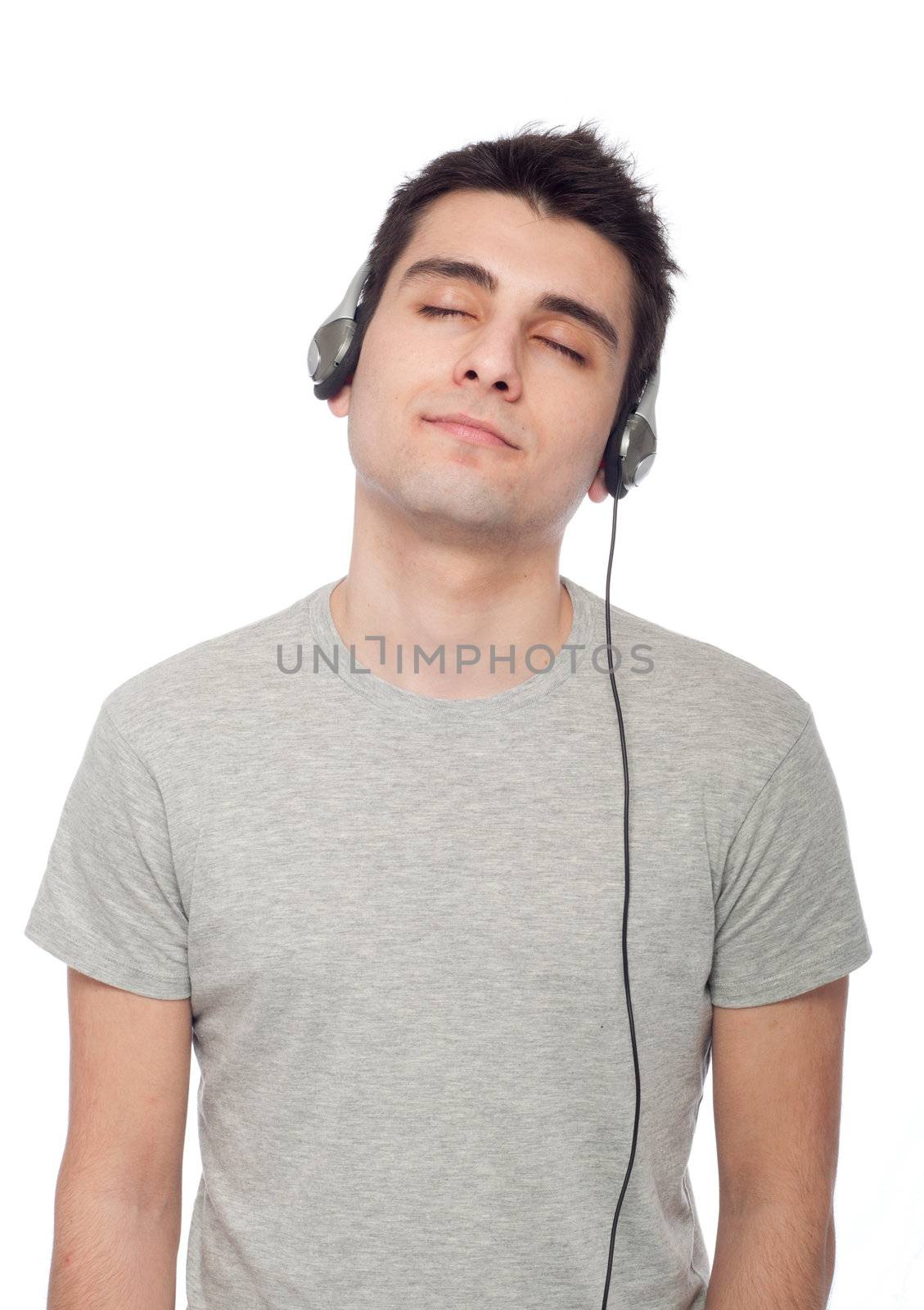 quiet casual young man listening music on headphones (isolated on white background)