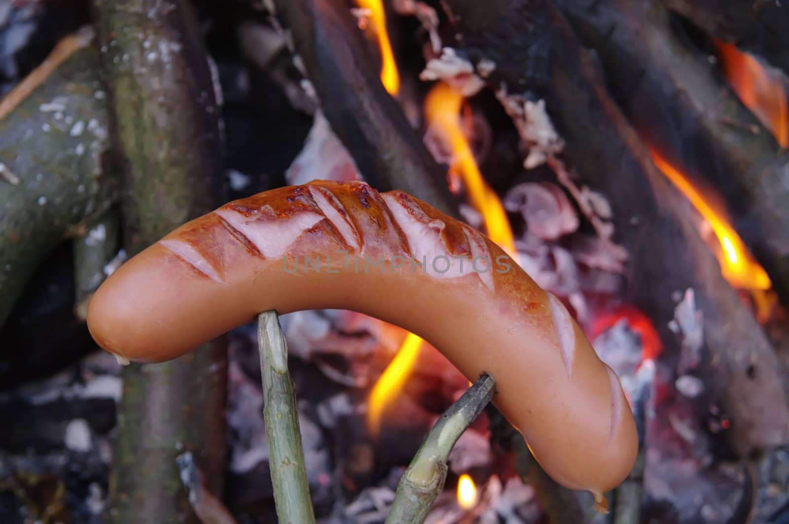 a sausage grilled on a camp fire