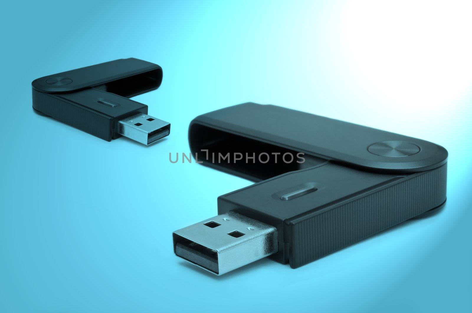 Close and low level angle capturing two black usb sd card adaptors arranged over blue light filter.