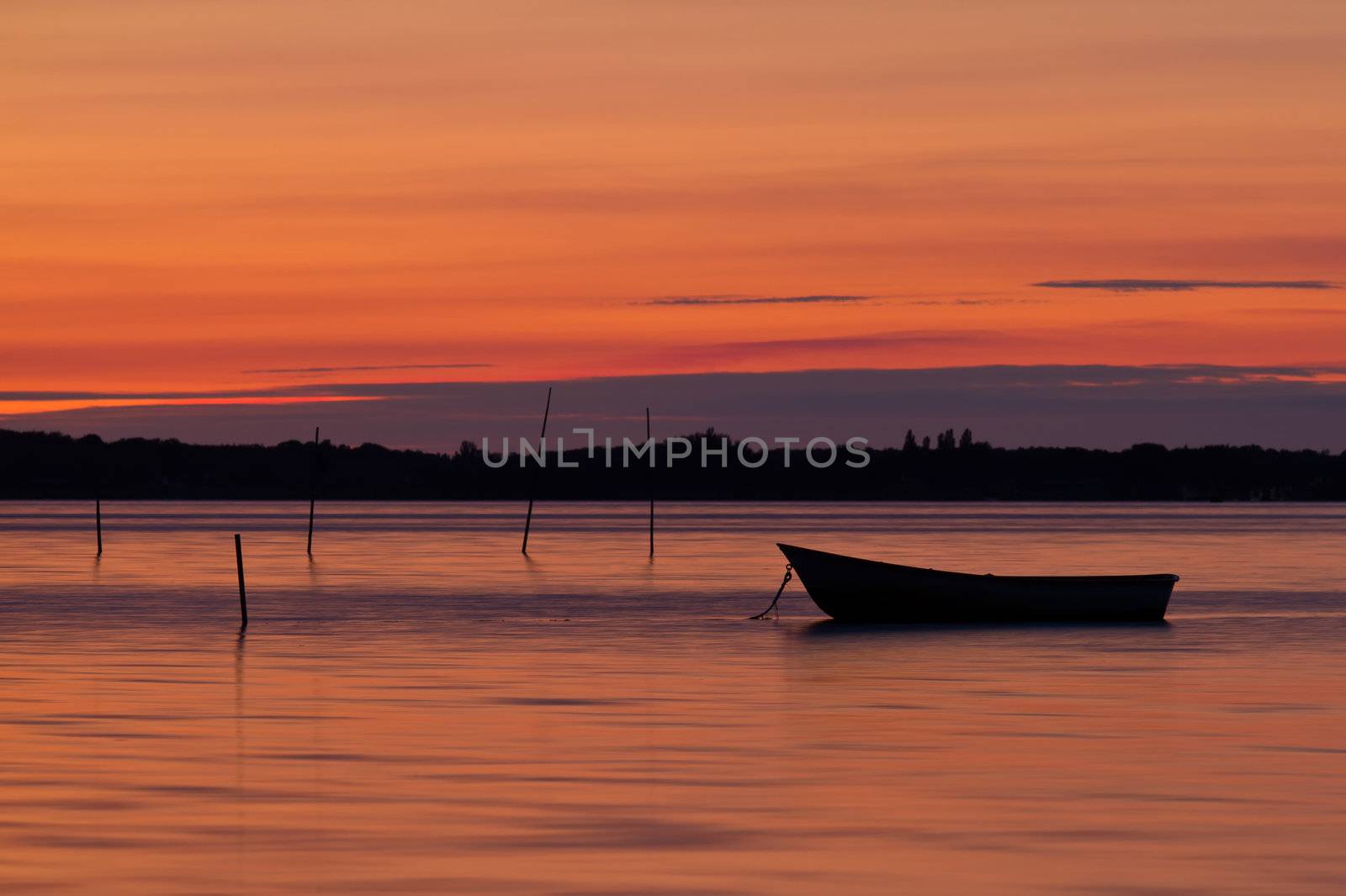 Scenic view of small fishing boat at sunset with cloudscape background.