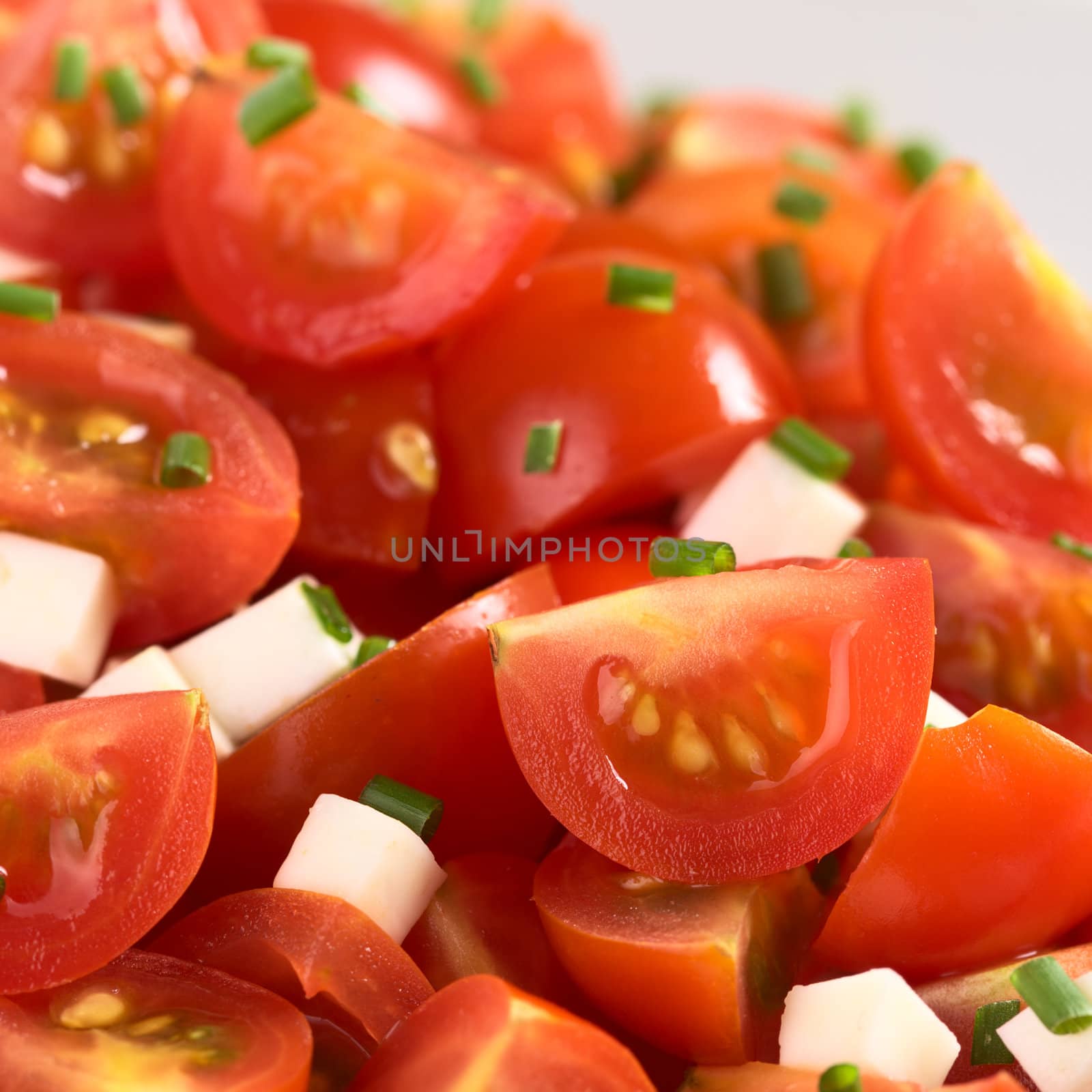 Cherry tomato wedges with cheese and chives prepared as salad (Selective Focus, Focus one third into the picture)